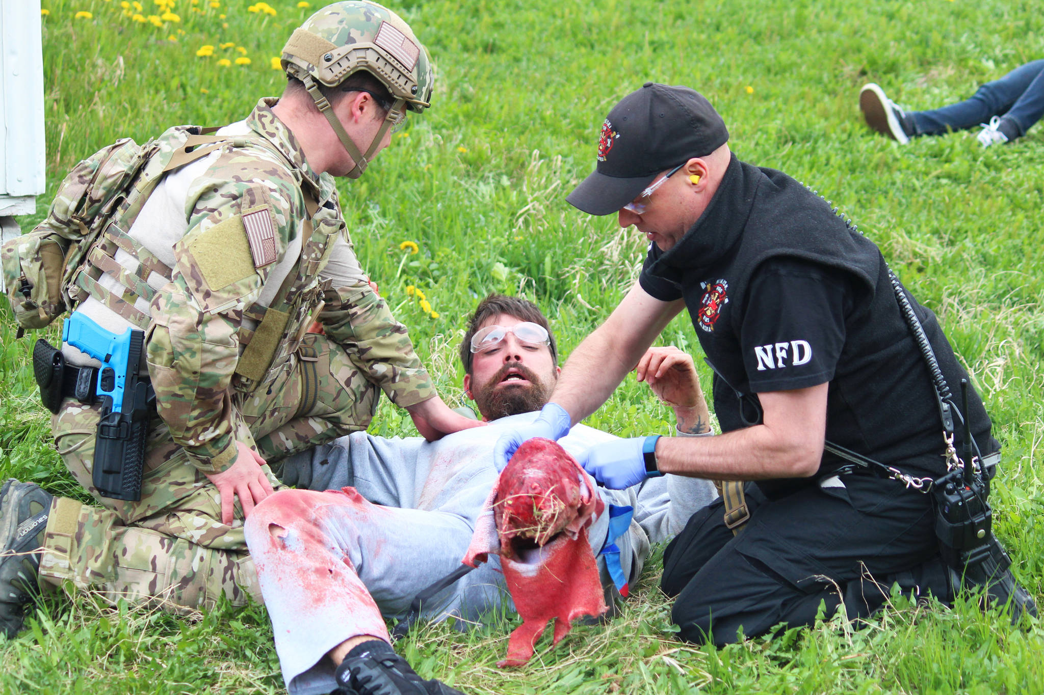 Arizona resident Nathan Lieber, a trauma amputee actor, looks at his own fake injuries casued by a simulated meth lab explosion while two local law enforement and emergency medical services personnel tend to him during a training drill Saturday, May 20, 2017 at the North Peninsula Recreation Center in Nikiski, Alaska. Lieber works for JTM Training Group, based out of Las Vegas, which travels to Alaska every year to conduct several multi-day training courses for members of law enforcement, corrections and medical first responders to practice working together in emergencies that turn violent. (Megan Pacer/Peninsula Clarion)