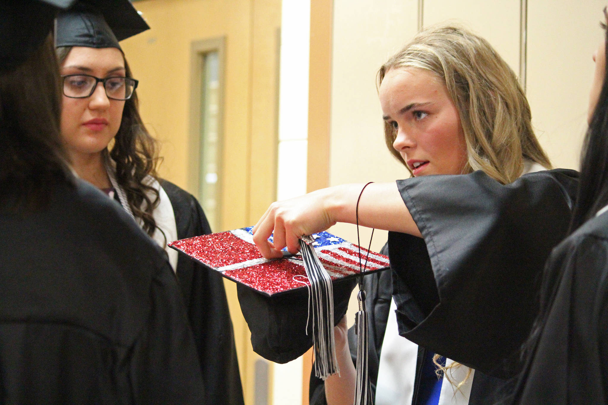 Sofie Nielsen, 16, secures a tassel onto her graduation cap just before walking with the 2017 graduating class of Nikiski Middle-High School on Tuesday, May 23, 2017 at the school’s gymnasium in Nikiski, Alaska. A foreign exchange student from Denmark, Nielsen will return home to complete high school this fall, but said she couldn’t pass up the opportunity to walk with her classmates when offered the chance. (Megan Pacer/Peninsula Clarion)