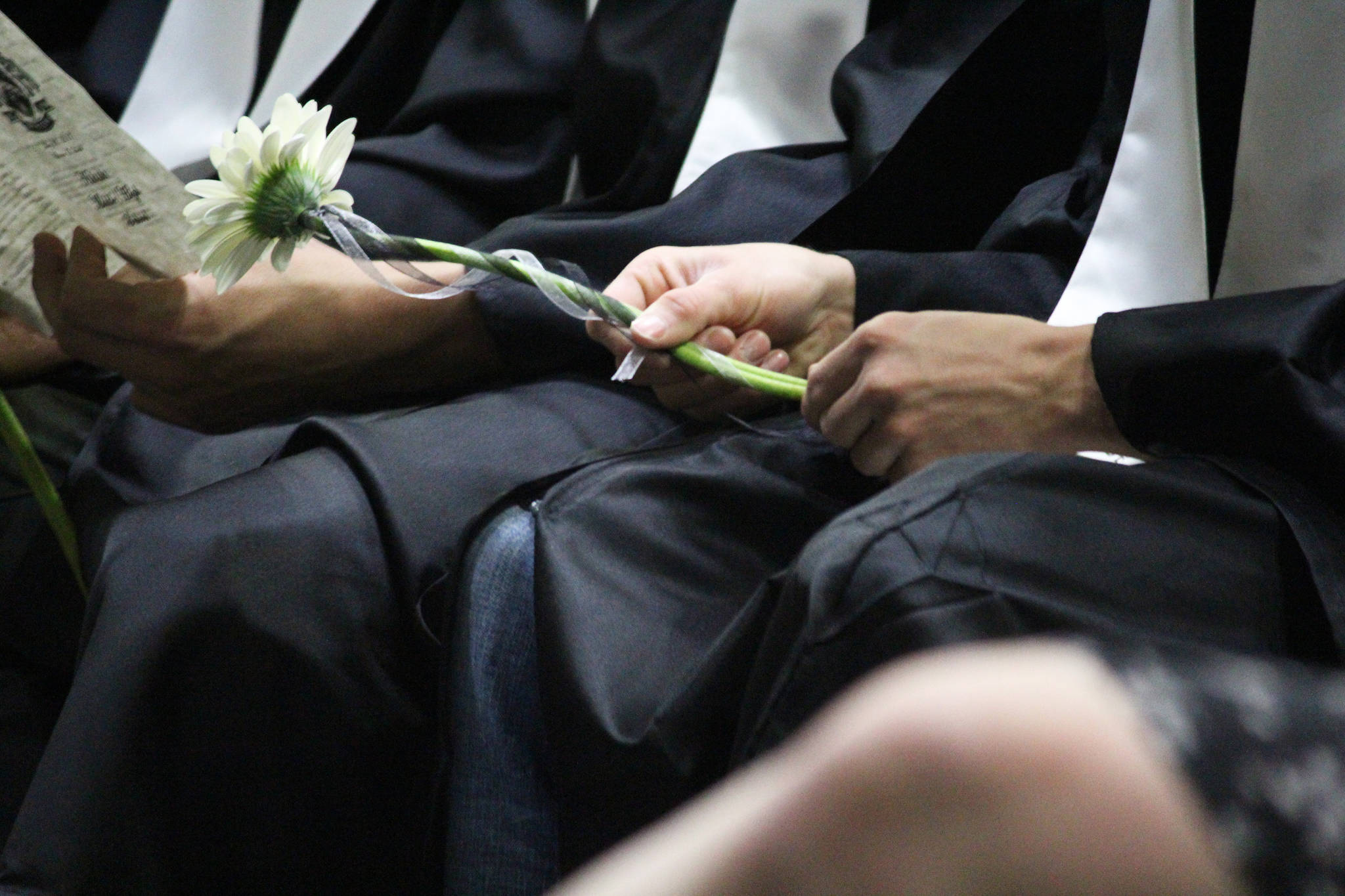A graduate of Nikiski Middle-High School fidgets with his flower, which all the students carried, during the graduation ceremony Tuesday, May 23, 2017 at the school gymnasium in Nikiski, Alaska. (Megan Pacer/Peninsula Clarion)
