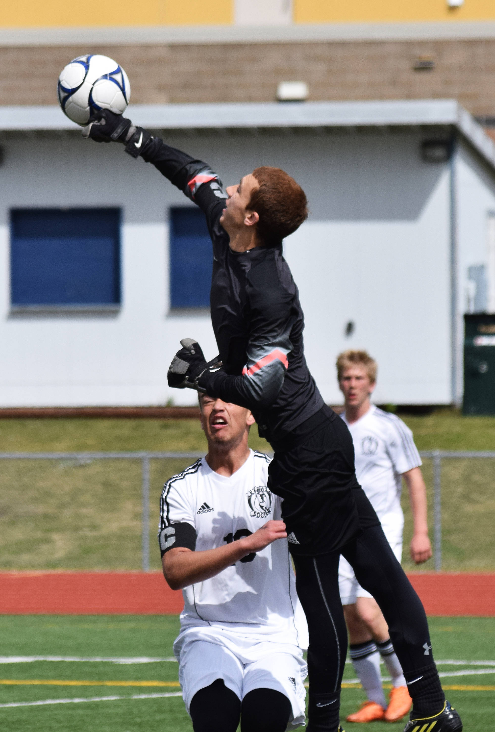 Kenai Central goalkeeper Tristan Landry bats the ball away following a Juneau-Douglas shot attempt Thursday at the state soccer tournament at Eagle River High School. (Photo by Joey Klecka/Peninsula Clarion)