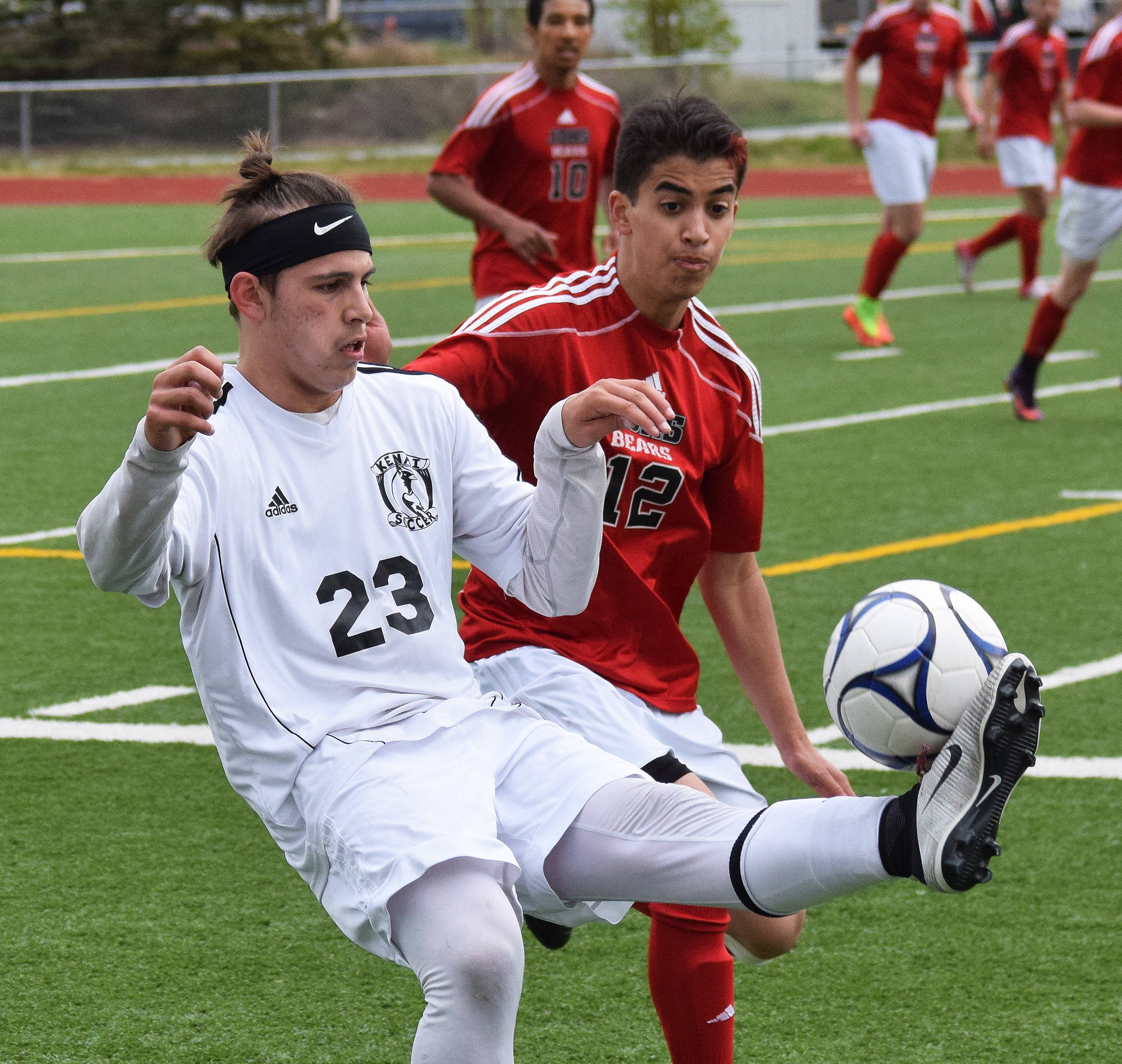 Kenai Central’s Zack Tuttle (23) keeps the ball away from Juneau-Douglas’ Salar Peirovi in a state soccer tournament quarterfinal Thursday at Eagle River High School. (Photo by Joey Klecka/Peninsula Clarion)