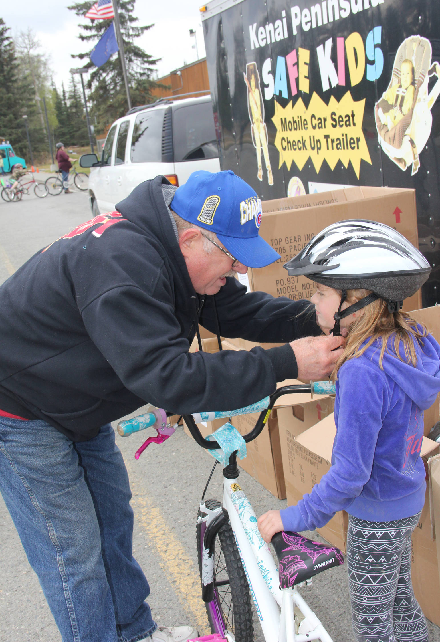 Retired CES Fire Marshal Gary Hale properly fits a bike helmet at Redoubt Bike Rodeo.