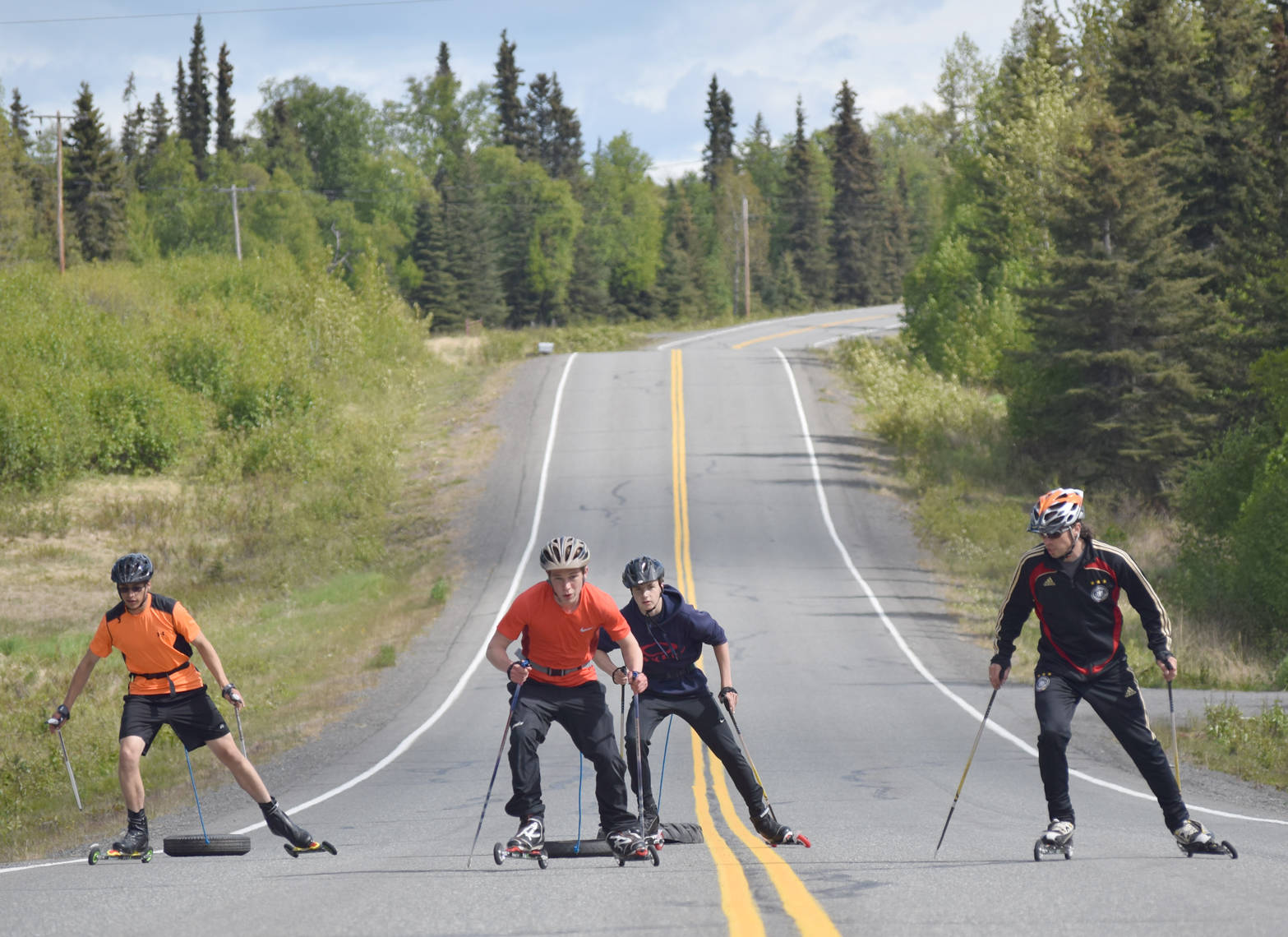 Soldotna sophomore Bradley Walters, Kenai Central junior Trevor Debnam and Soldotna sophomore Jack Harris pull tires up a hill on South Coho Loop under the watch of Andy Liebner on Monday.