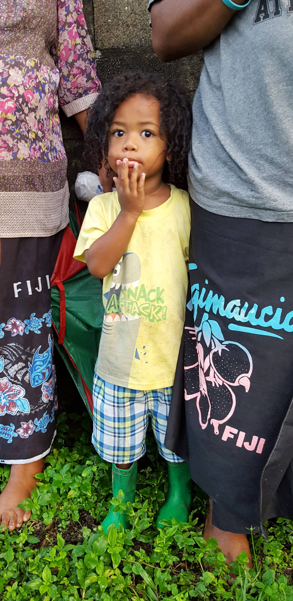 A Waitabu boy hides behind his mother and aunt while the village sings Isa Lei, their traditional Fijian farewell song. (Photo courtesy Tracy Melvin)