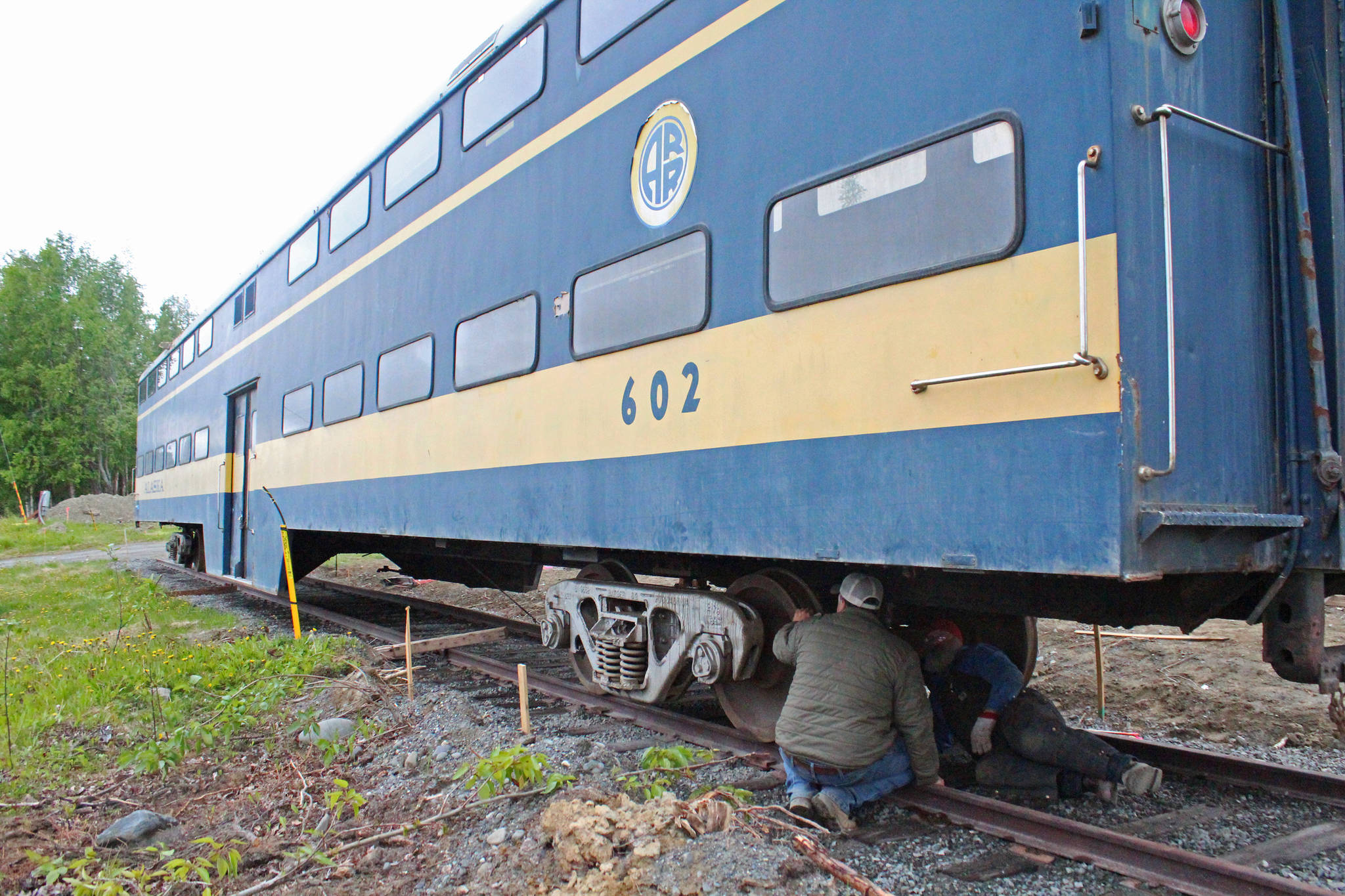 Glenn Fowler of excavation company Fowler’s Dirt Works, left, and Doug Bass of Bass Werks Welding, right, scope out the underside of Alaska Railroad rail car 602 on Thursday, June 8, 2017 in Soldotna, Alaska. The rail car was placed onto a set of trucks, the wheels underneath the car, where it will be fixed in place an eventually turned into a coffee house. Mary Krull hopes to open the coffee house and a beer and wine bar/restaurant in a second rail car by next year. (Megan Pacer/Peninsula Clarion)