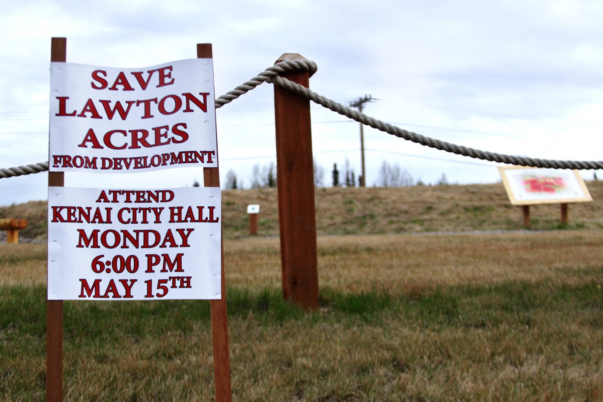 A sign posted near the Kenai Field of Flowers by activist and nieghborhood resident Greg Daniels urges property-owners near Lawton Acres — a 16.5-acre wooded strip of city-owned land that has been the subject of controversial development efforts — to attend a past Kenai City Council meeting, phographed on May 12, 2017 in Kenai, Alaska. The Kenai City Council may vote on June 21 or July 5 on whether to preserve Lawton Acres as a park by paying to relieve it from the legal obligation to support the Kenai Municipal Airport.