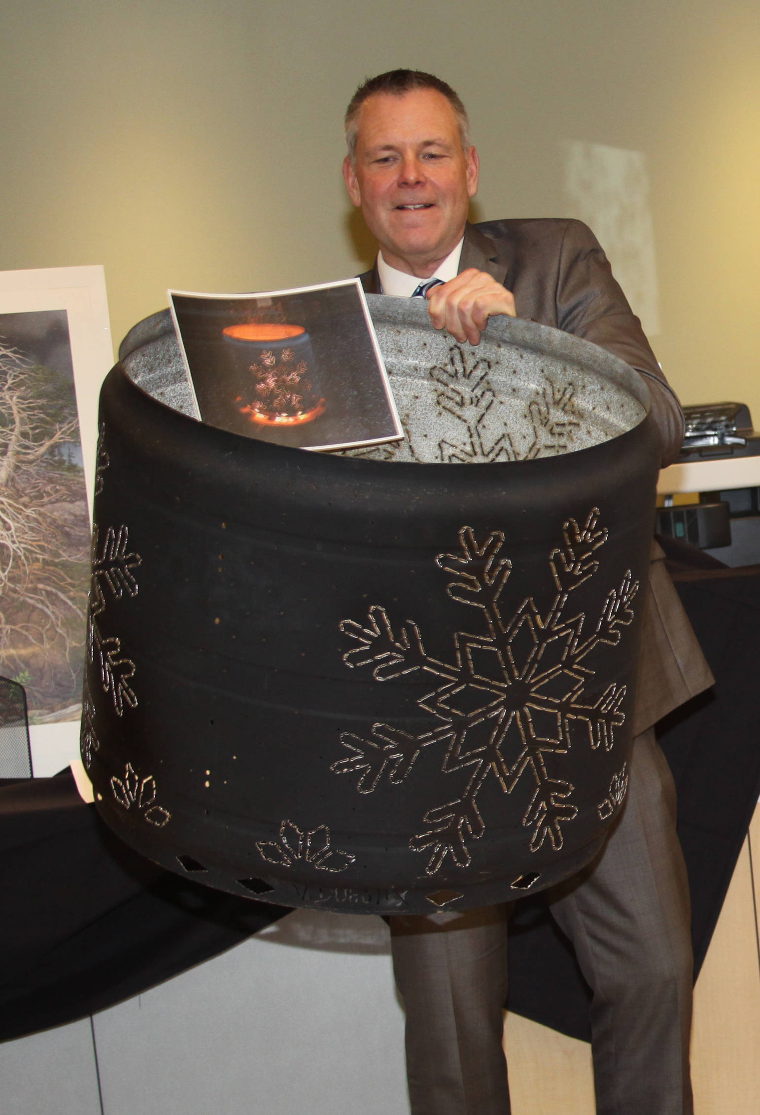 CPH Finance Director Bruce Richards holds an artistic burn barrel up for bid at Evening by the River.