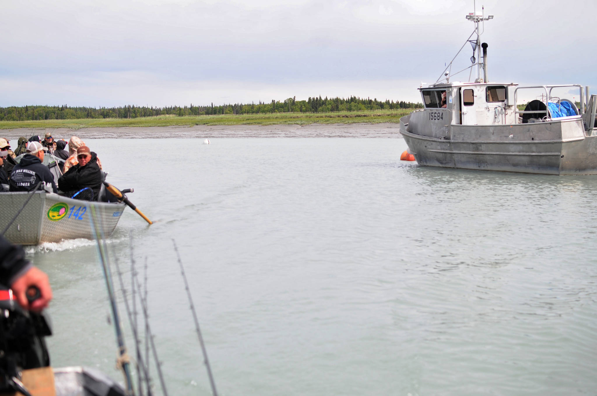 Bill Russell, a fishing guide at Russell Fishing Company, tows two fishing boats full of clients past a docked commercial fishing vessel on the Kasilof River on Monday, June 19, 2017 in Kasilof, Alaska. (Photo by Elizabeth Earl/Peninsula Clarion)