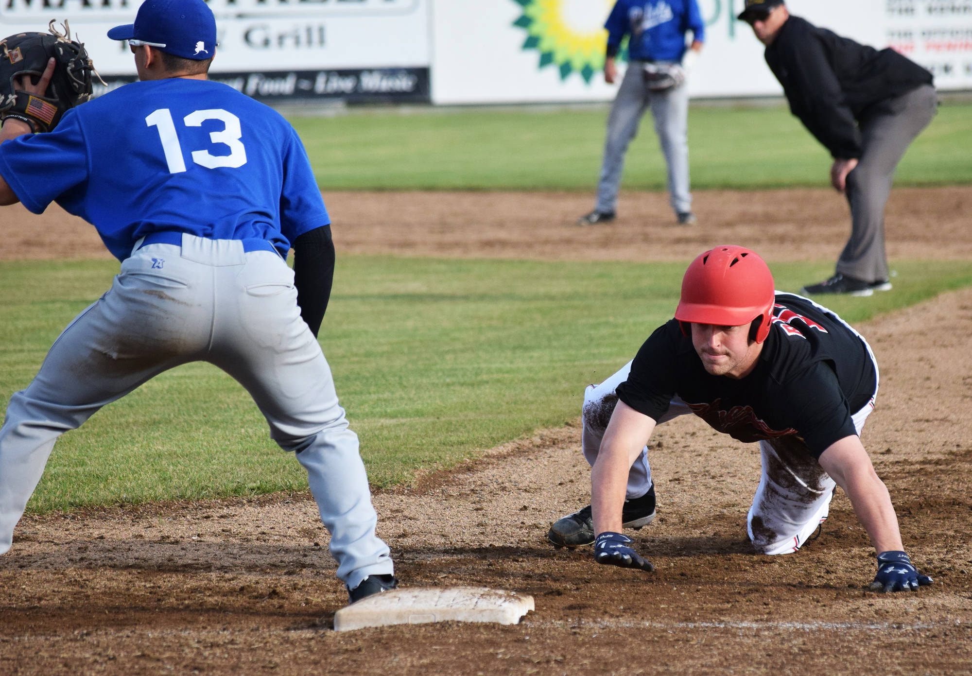 Peninsula Oilers baserunner Thomas Ruddy tags up to first base ahead of the glove of Ian Evans of the Anchorage Glacier Pilots, Friday evening at Coral Seymour Memorial Park in Kenai. (Photo by Joey Klecka/Peninsula Clarion)