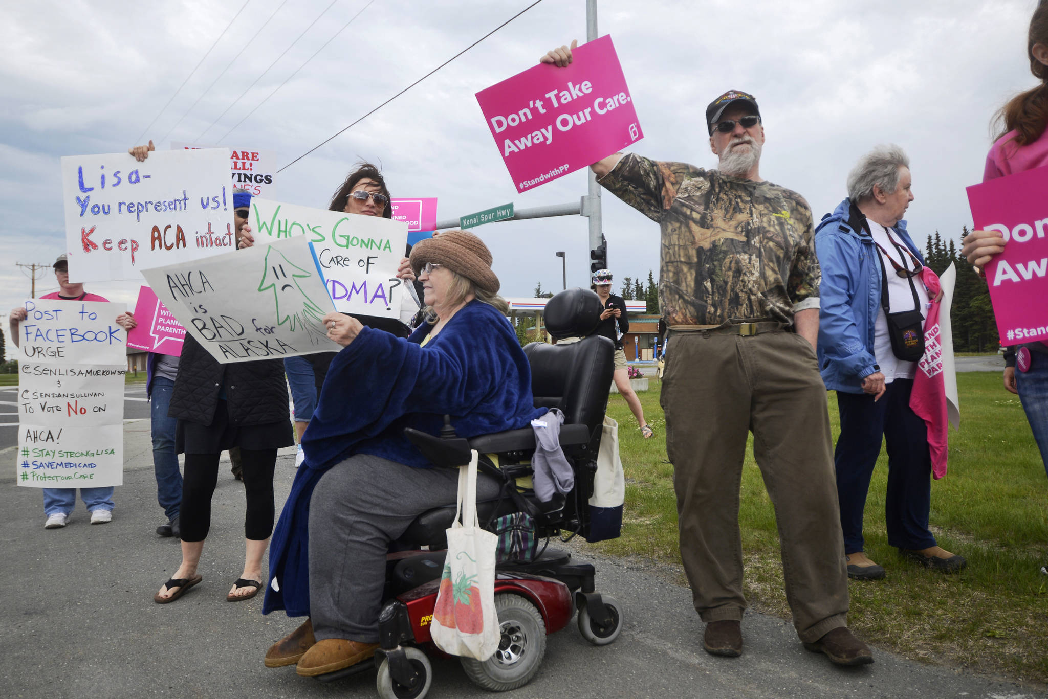 Linda Nelson (in wheelchair) and her husband Rodney Nelson hold signs in a demonstration by supporters of women’s health organization Planned Parenthood and opponents of the U.S Senate healthcare bill known as the Better Care Reconciliation Act on Thursday, July 6, 2017 in Kenai, Alaska. (Ben Boettger/Peninsula Clarion)