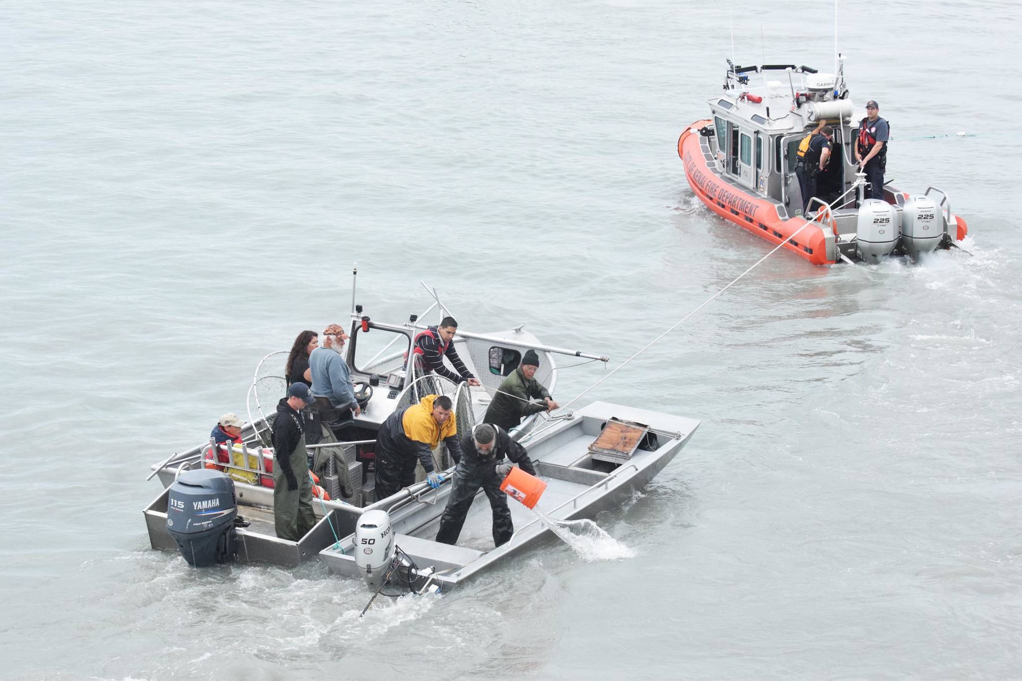 Members of the Kenai Fire Department and Kenai Police Department tow two boats behind them, one that capsized and another that came to the rescue, while passengers work to bail out the capsized boat July 22, 2016 on the Kenai River in Kenai, Alaska. (File photo by Megan Pacer/Peninsula Clarion)