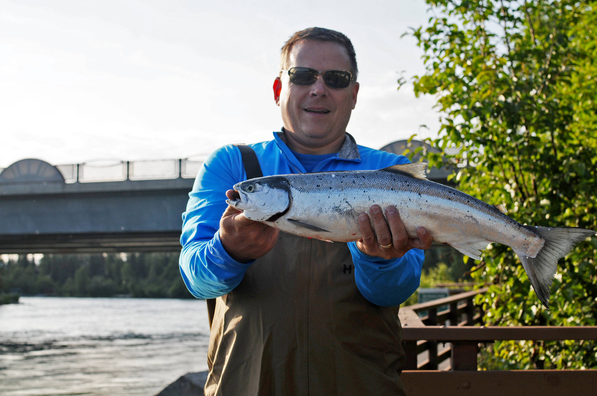 Tom Lyman of Michigan holds up a sockeye salmon he caught in the Kenai River on Wednesday, July 12, 2017 in Soldotna, Alaska. Lyman, who is visiting Alaska with his son, said he hadn’t been casting for long when he hooked into the fish. (Photo by Elizabeth Earl/Peninsula Clarion)