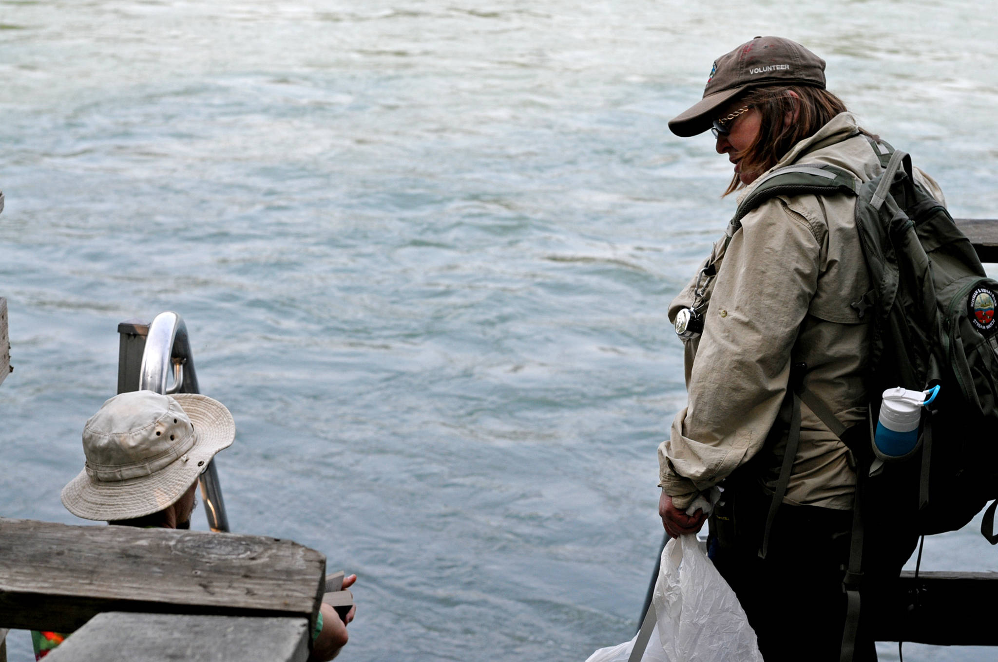 Kathy Heindle (right), a Kenai Peninsula Stream Watch volunteer, speaks to a man on one of the fishing access stairs during one of her Kenai Peninsula Stream Watch walks in Centennial Park on Thursdayin Soldotna. Heindle, who has been volunteering with Stream Watch since 2011, received a “Kingmaker” award from the Kachemak Heritage Land Trust for her work protecting the Kenai River watershed. (Photo by Elizabeth Earl/Peninsula Clarion)