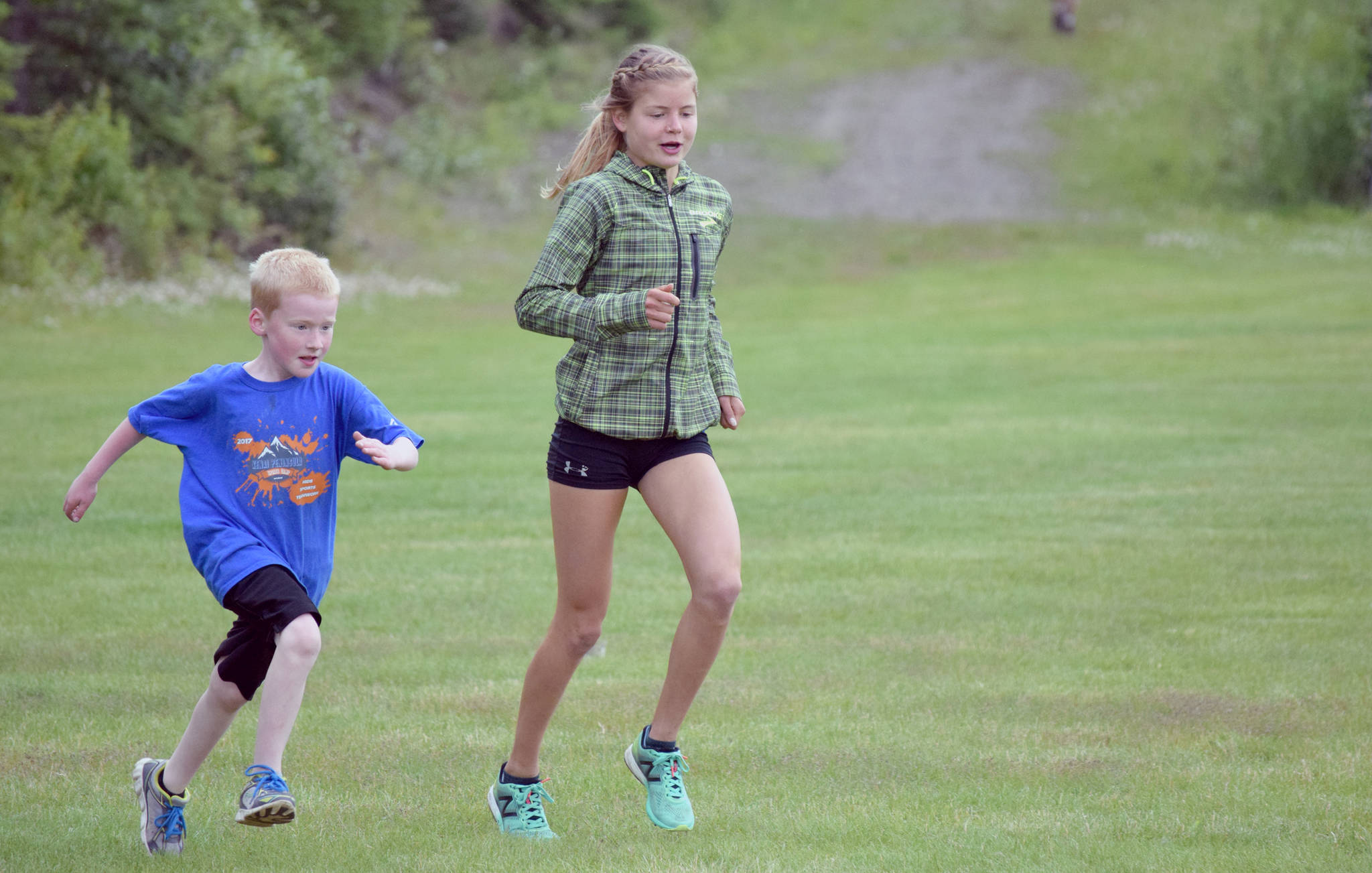 Allie Ostrander paces Joshua Lattin, 6, of Soldotna during the one-kilometer kids race at the Salmon Run Series at Tsalteshi Trails in Soldotna on Wednesday, July 19, 2017. (Photo by Jeff Helminiak/Peninsula Clarion)