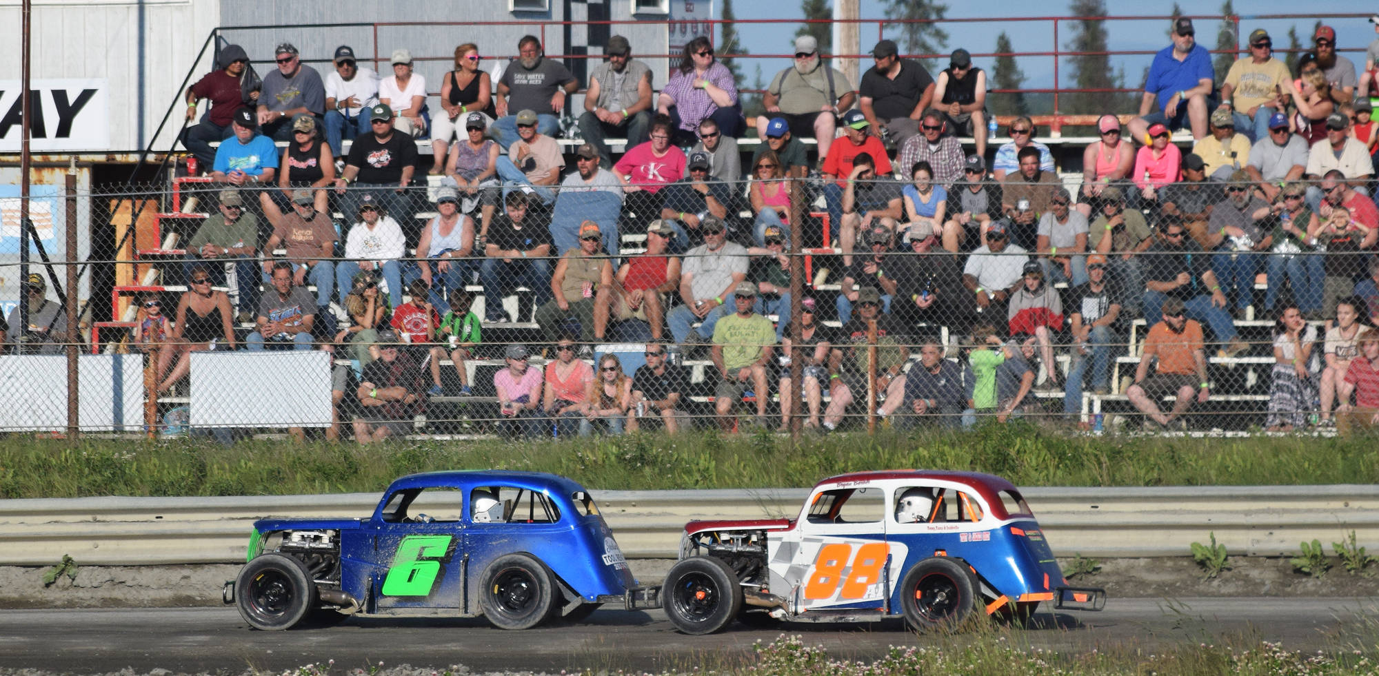 A full crowd watches as Legends drivers Brent Ramagoux (6) and Bryan Barber race for position during the running of the Alaska Dirt Track Shootout held Saturday at Twin City Raceway in Kenai. (Photo by Joey Klecka/Peninsula Clarion)