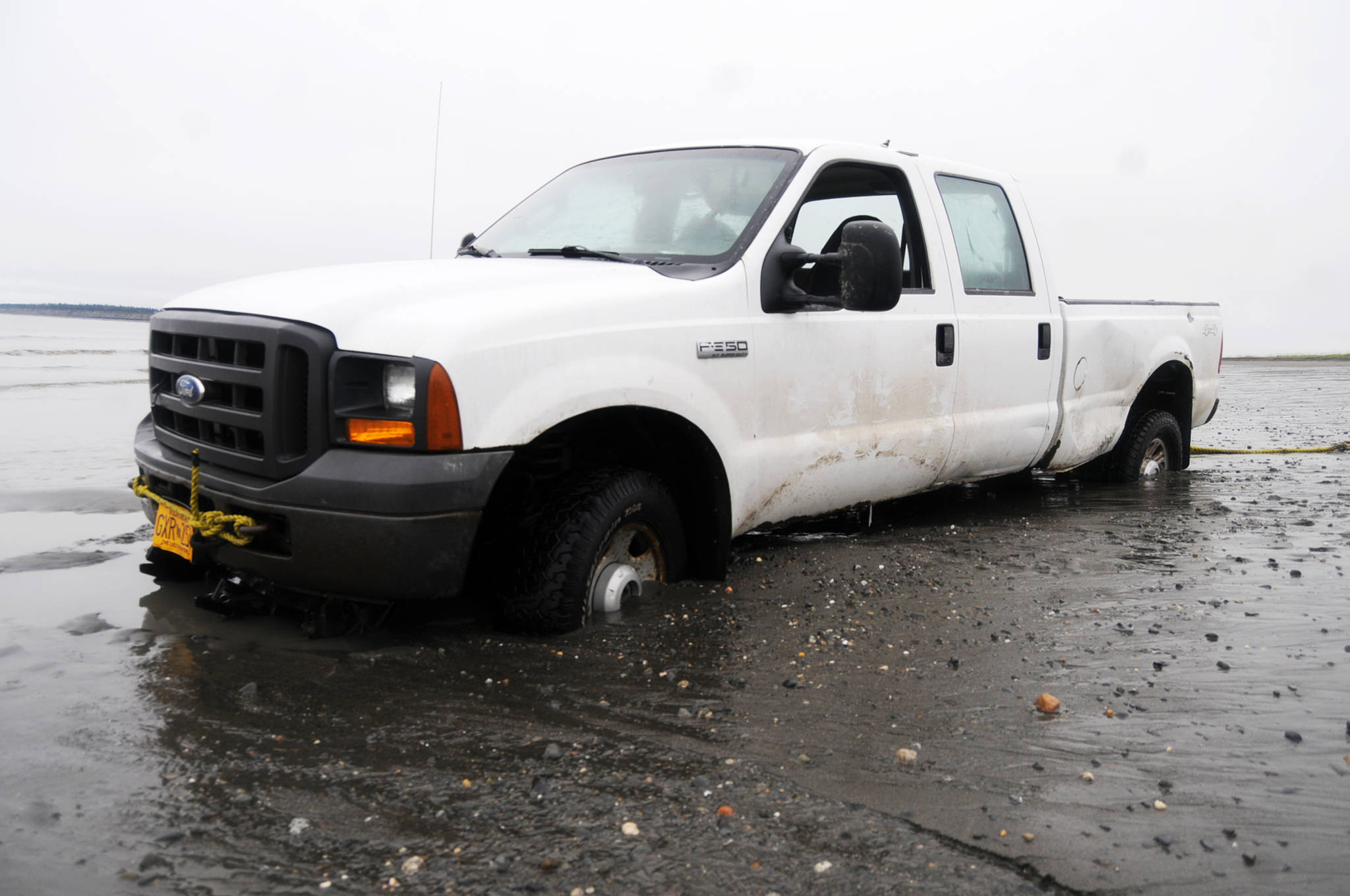 The muddy sand of the south Kenai beach traps Armin Schmidt’s pickup truck on Thursday, July 27, 2017 in Kenai, Alaska. Schmidt, a commercial set gillnet fisherman, was driving the truck Wednesday when it sank into the spongy mud in the intertidal area of the south Kenai beach near the jersey barrier designating the legal personal-use dipnet area. He was working with the city of Kenai’s Parks and Recreation Department, which coordinates the dipnet, to get it it out Thursday. No one was hurt in the incident. (Photo by Elizabeth Earl/Peninsula Clarion)