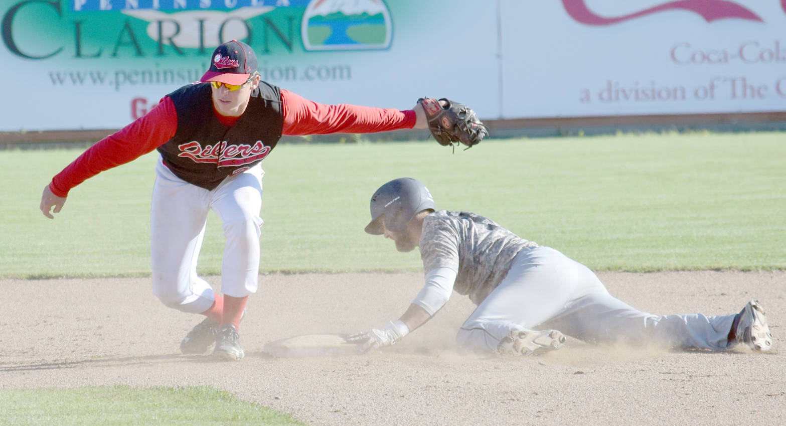 Adam Rojas of the Chugiak-Eagle River Chinooks slides under the tag of Oilers shortstop Caleb Hicks in the top of the second inning Thursday, July 27, 2017, at Coral Seymour Memorial Park in Kenai. (Photo by Jeff Helminiak/Peninsula Clarion)