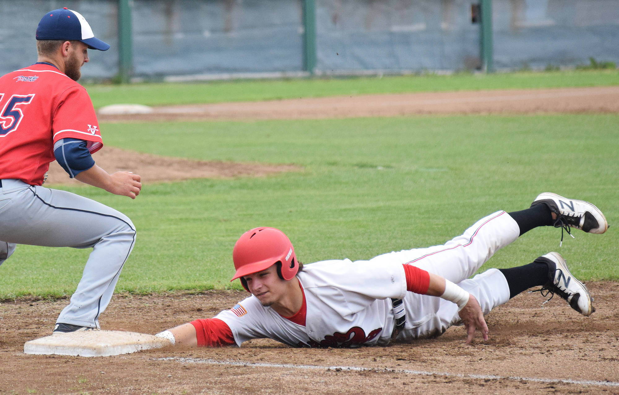 Peninsula Oilers baserunner Jack Bauer tags up to first base under the glove of Adam Rojas, Friday against the Chugiak Chinooks at Coral Seymour Memorial Ballpark in Kenai. (Photo by Joey Klecka/Peninsula Clarion)