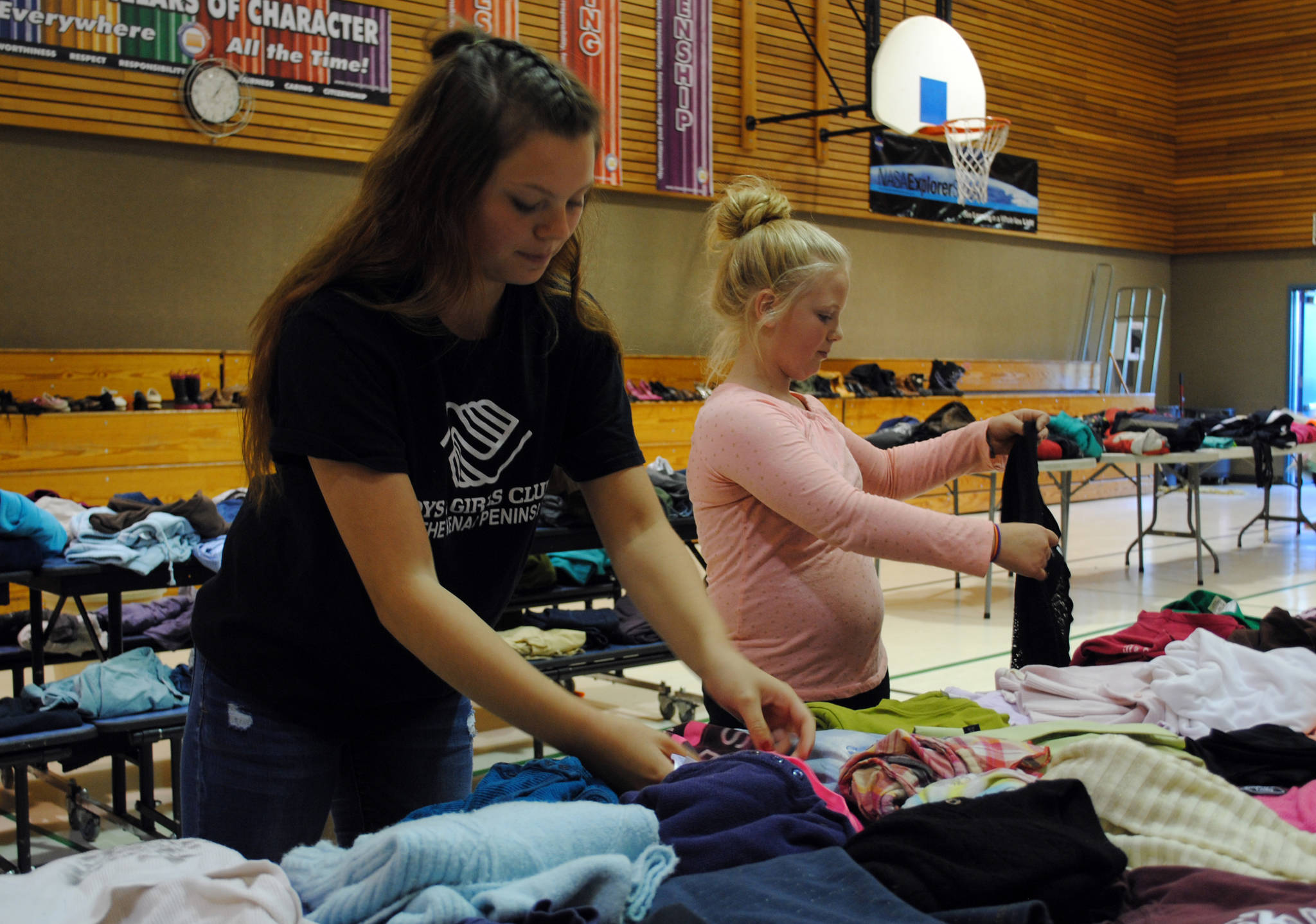 Tawnisha Freeman (left) and Giaseena Nicks of the Nikiski clubhouse with Boys and Girls Club of the Kenai Peninsula keep the tables organized Monday, July 31, 2017, at the free clothing, shoes and book event they helped organize. The event, which is held at Nikiski North Star Elementary School in Nikiski, Alaska, runs from 10 a.m. to 6 p.m. until Wednesday, August 2, 2017. (Photo by Kat Sorensen/Peninsula Clarion)