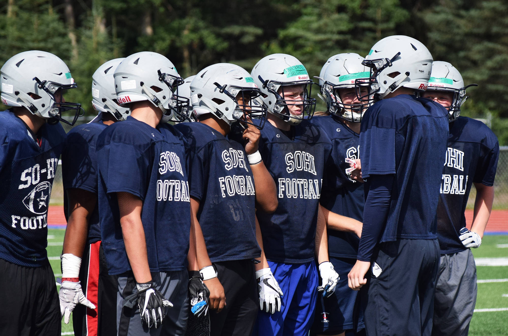A group of Soldotna players discuss play-calling in an Aug. 5 scrimmage against Chugiak at Justin Maile Field in Soldotna. (Photo by Joey Klecka/Peninsula Clarion)