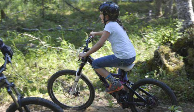 Lexi Larson eases her way down a banked turn on the Mosquito singletrack trail on July 2, 2014 at Tsaleteshi Trails in Soldotna. Work is under way to improve the original singletrack and add more to the trail system. (Clarion file photo)