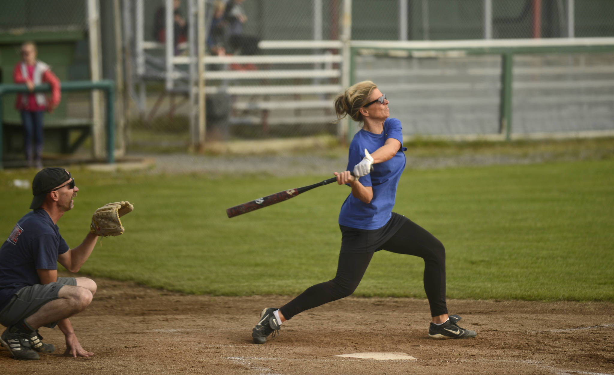 With Central Emergency Services’ Shawn Killian playing catcher, Soldotna Police Department disapatcher Tammy Goggia swings at an oncoming ball during a charity softball game for the Nikiski Children’s Fund between local law enforcers and firefighters on Thursday, August 18 at Kenai’s Oiler’s Field. Law enforcement won the game 17-7, but made no arrests for stolen bases. The Nikiski Children’s Fund, founded last year by Carlee Rizzo, makes money available to to teachers and other community members to fill needs they see for local children. Rizzo said the group has more fundraisers planned for the future, such as a show in September by the rock trio No Small Children.