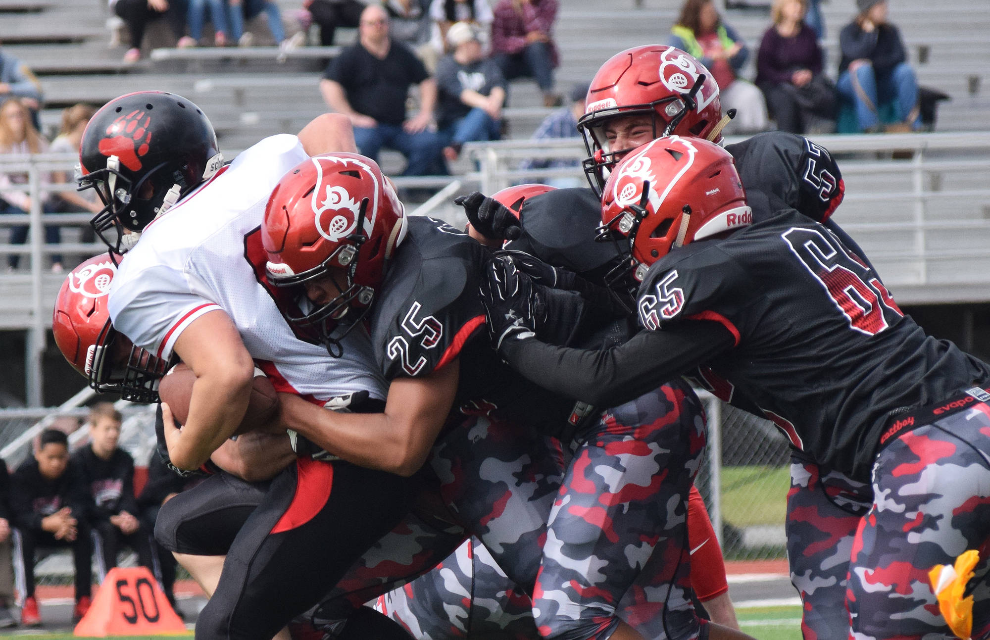Juneau running back Liam Van Sickle gets tackled by several Kenai defenders, including James Siamani (25) and John Grossl (65) Saturday afternoon at Ed Hollier Field in Kenai. (Photo by Joey Klecka/Peninsula Clarion)