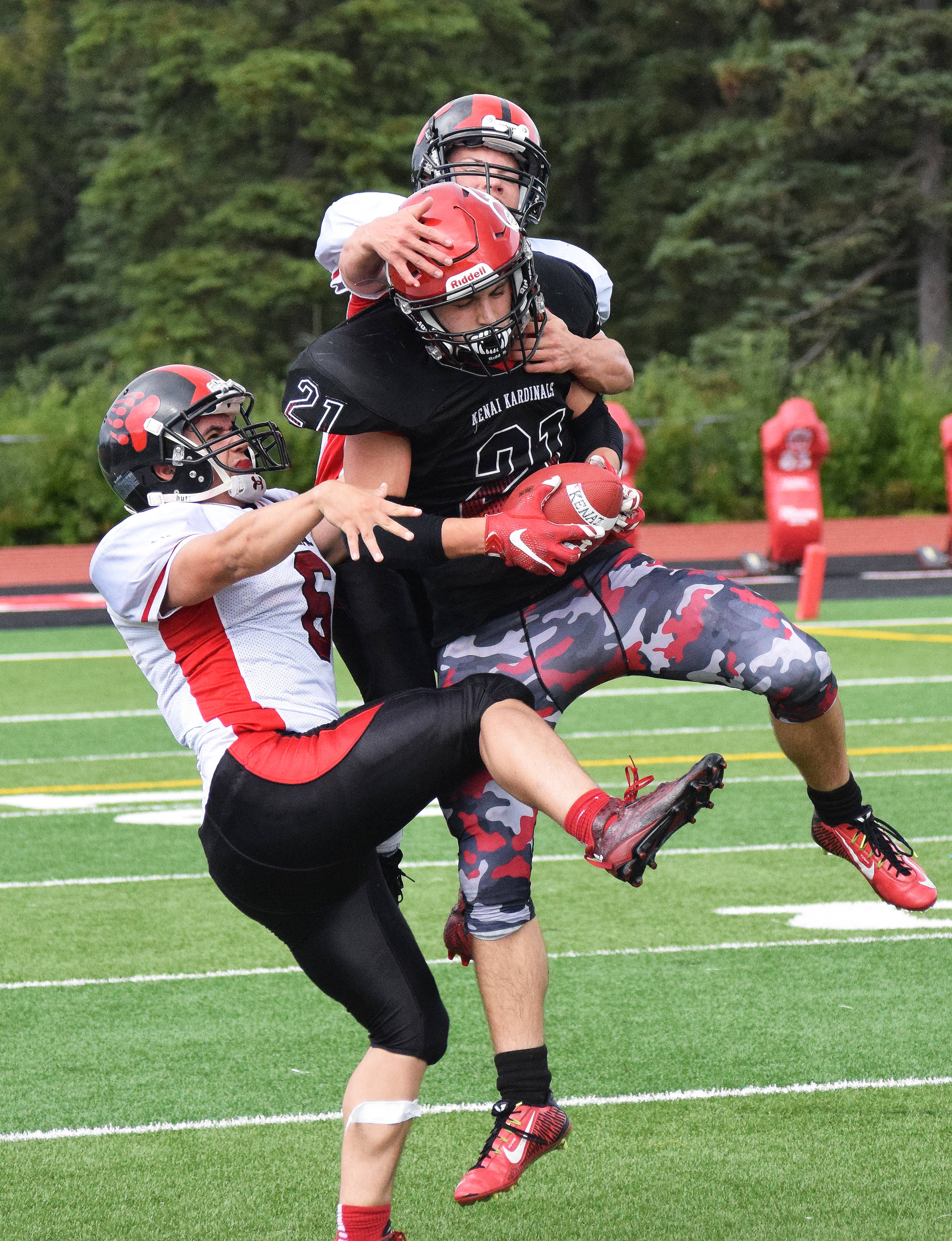 Kenai Central senior Zack Tuttle hauls in a long pass from quarterback Connor Felchle as Juneau defensive backs Donavin McCurley (right) and Liam Van Sickle hang on, Saturday afternoon at Ed Hollier Field in Kenai. (Photo by Joey Klecka/Peninsula Clarion)