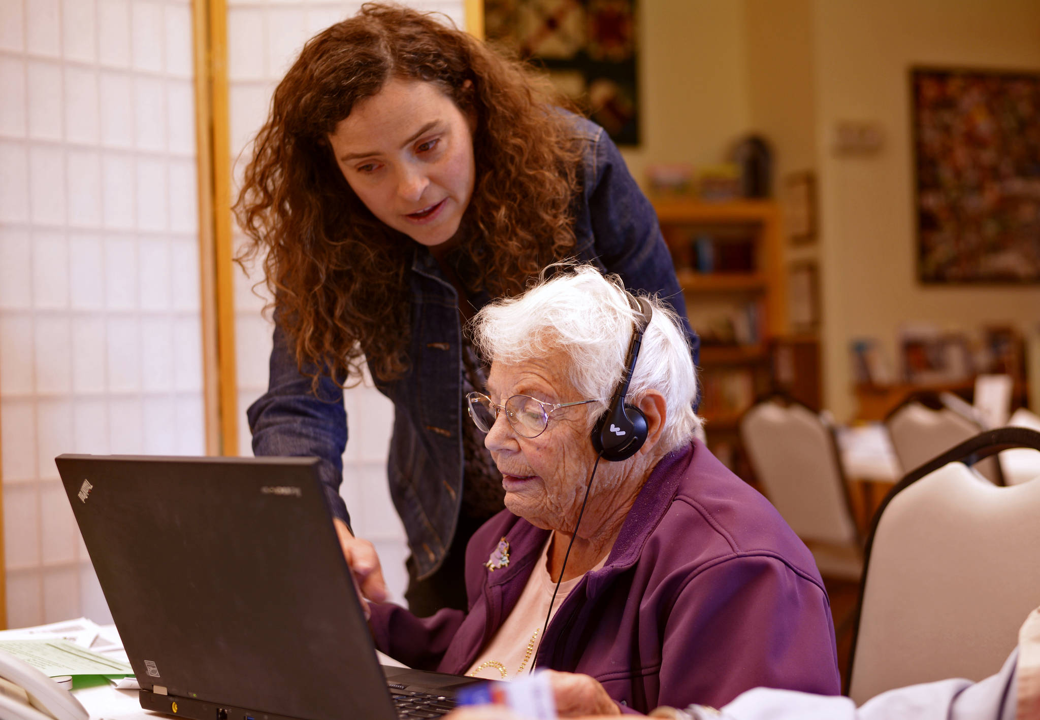 Putting technology to work Mariana Livingston (standing) of Assistive Technology of Alaska guides Brad Rooker through demonstrations of a hearing device and software that enlarges and enhances the contrast of digital text for the visually impaired on Wednesday at the Kenai Senior Center. Livingston’s Anchorage-based group was one of four at the senior center to hold a health fair and one-on-one clinics for those interested in aid devices for vision, hearing, and mobility. Others included the Independent Living Center, the Alaska Center for the Blind, and the Kenai Centenial Savvy Lions Club, which offered free vision exams. Independent Living Center office manager Melissa Kline said the groups hope to hold the event annually in Kenai in the fall and at the Soldotna Senior Center in the spring. (Ben Boettger/Peninsula Clarion)