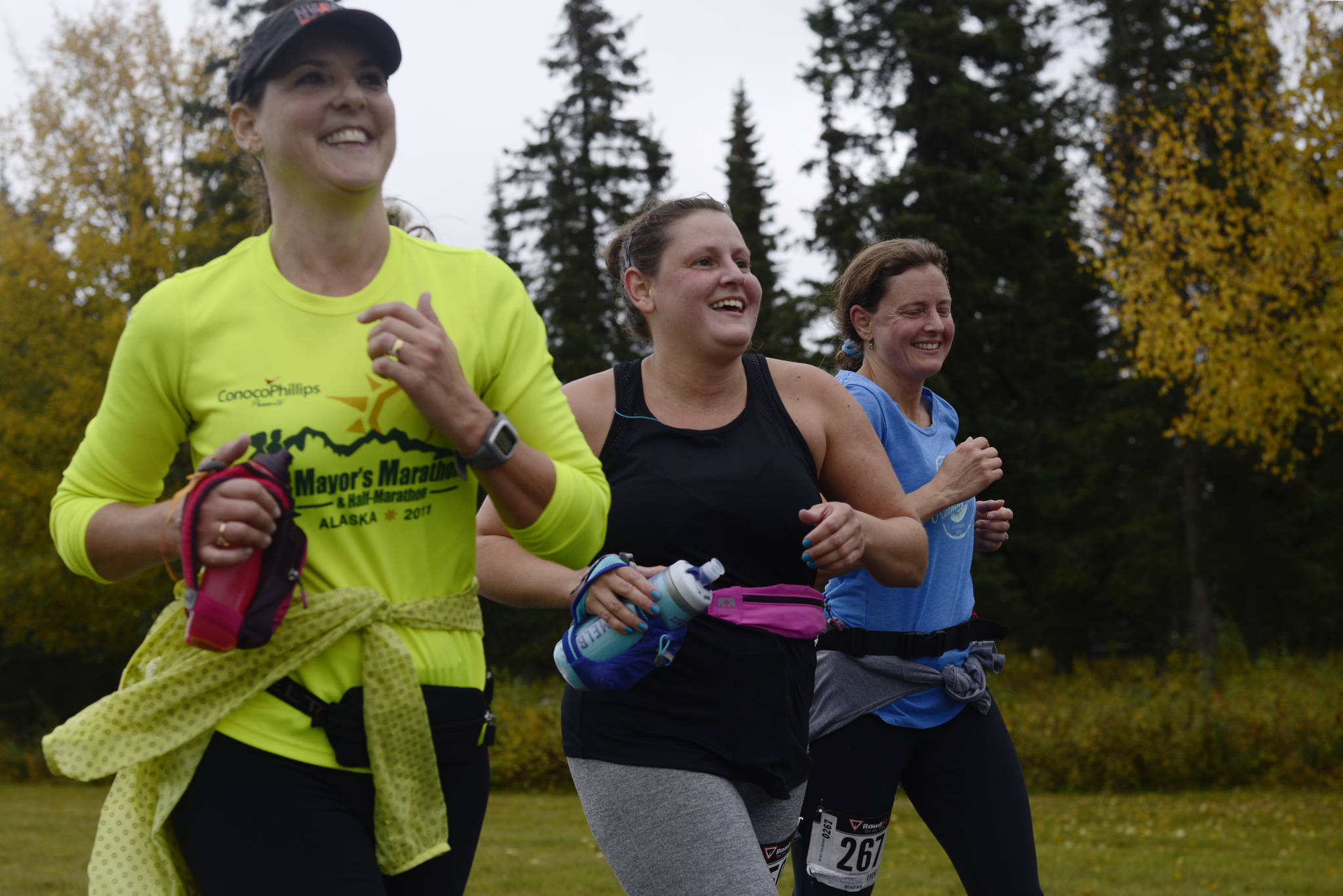 Runners Kimberly Buskirk (left), Kate Swaby, and Candace Cartwright run in the Kenai River half-marathon on Sunday, Sept. 24, 2017 in Kenai, Alaska.