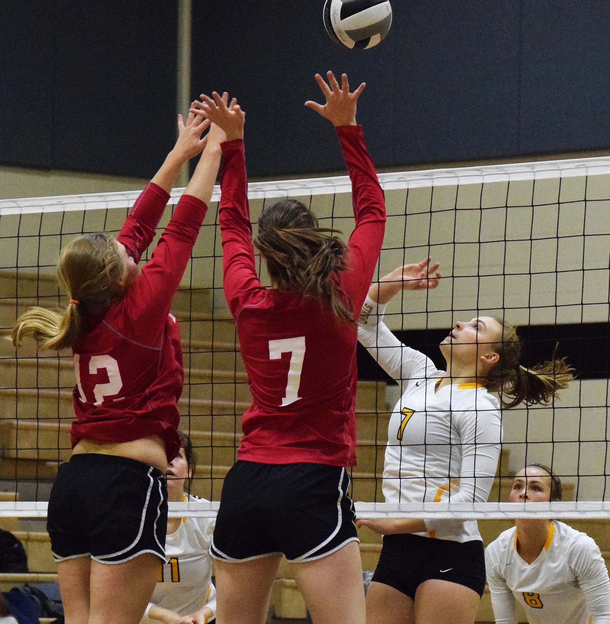 Nikiski junior Bethany Carstens attempts to spike a ball by Anchorage Christian middle hitters Kira Keller (12) and Kelsey Smallwood (7) Friday at Nikiski High School. (Photo by Joey Klecka/Peninsula Clarion)