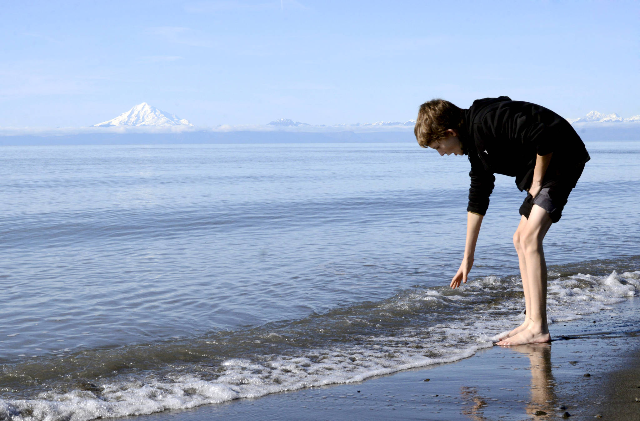 Gavin Graves braves the cold water of the Cook Inlet to beach comb along the beach in Kenai, Alaska on Saturday, October 1, 2017. (Photo by Kat Sorensen/Peninsula Clarion)