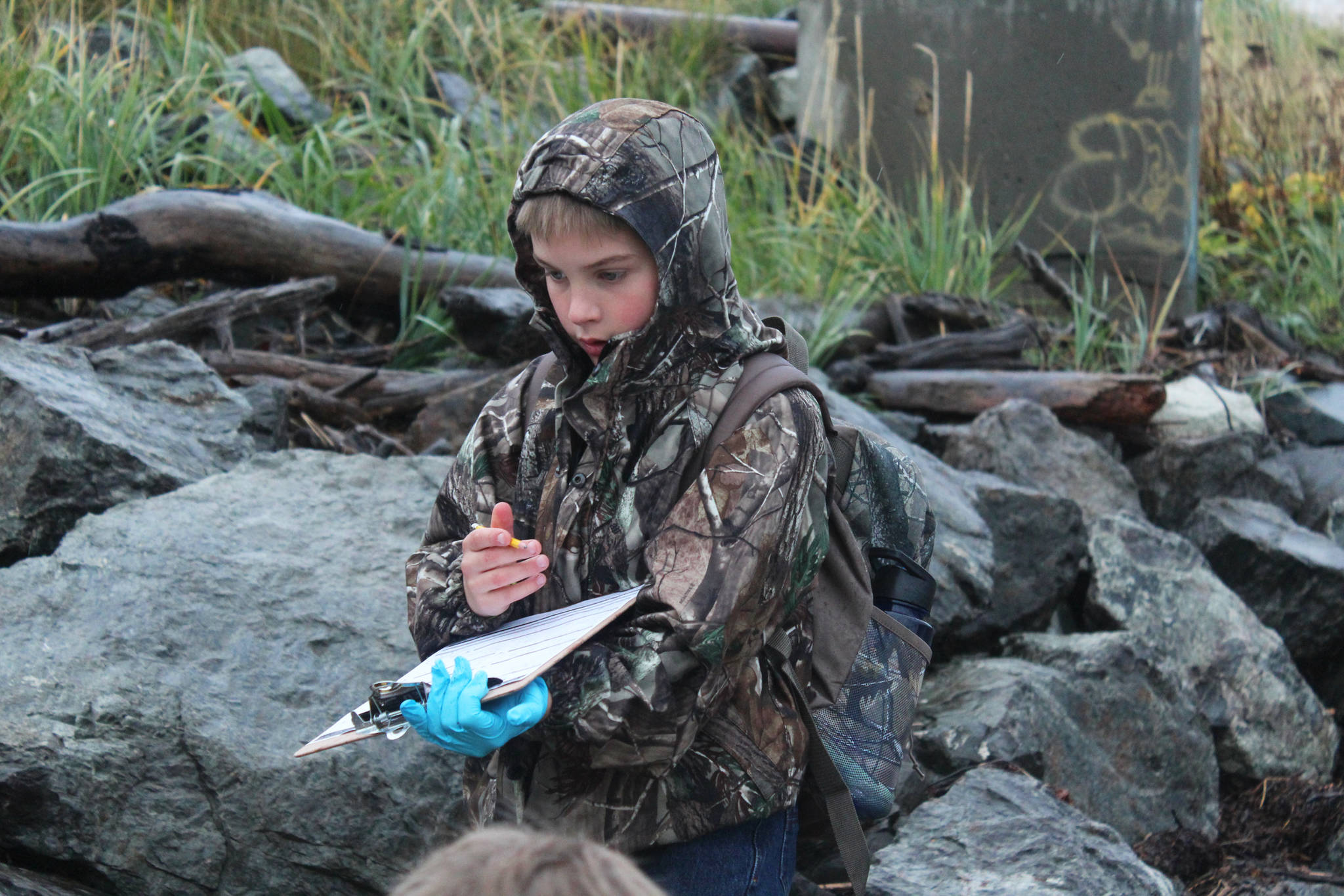 Tanner Johnson, a fourth grader at McNeil Canyon Elementary School, marks down his group’s findings on a clipboard while he and classmates clean the shoreline on Friday, Sept. 22 near Mariner Park in Homer. Many school classes and citizen groups sign up each year to scour a section of coast during the annual Kachemak Bay CoastWalk, hosted by the Center for Alaskan Coastal Studies. (Photo by Megan Pacer/Homer News)