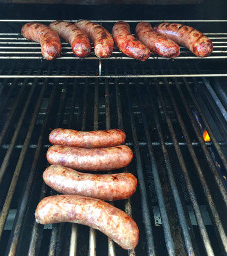 This Sept. 17, 2017 photo shows bratwurst sausages being grilled before simmering in beer in Houston. This dish is from a recipe by Elizabeth Karmel. (Elizabeth Karmel via AP)