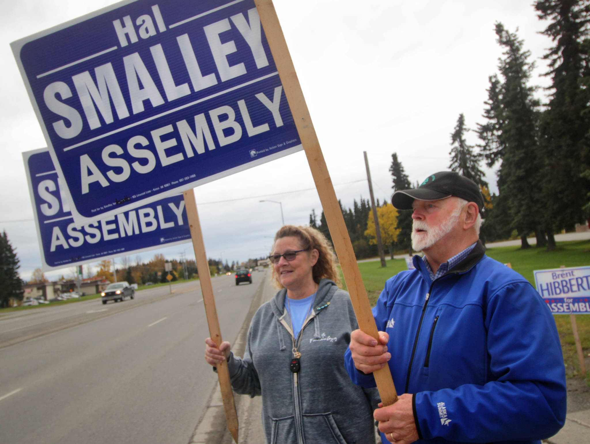 Kenai Peninsula Bourough assembly candidate Hal Smalley and supporter Michele Vasquez wave signs near the intersection of the Kenai Spur Highway and Bridge Access Road on Tuesday, Oct. 3 in Kenai. (Ben Boettger/Peninsula Clarion)