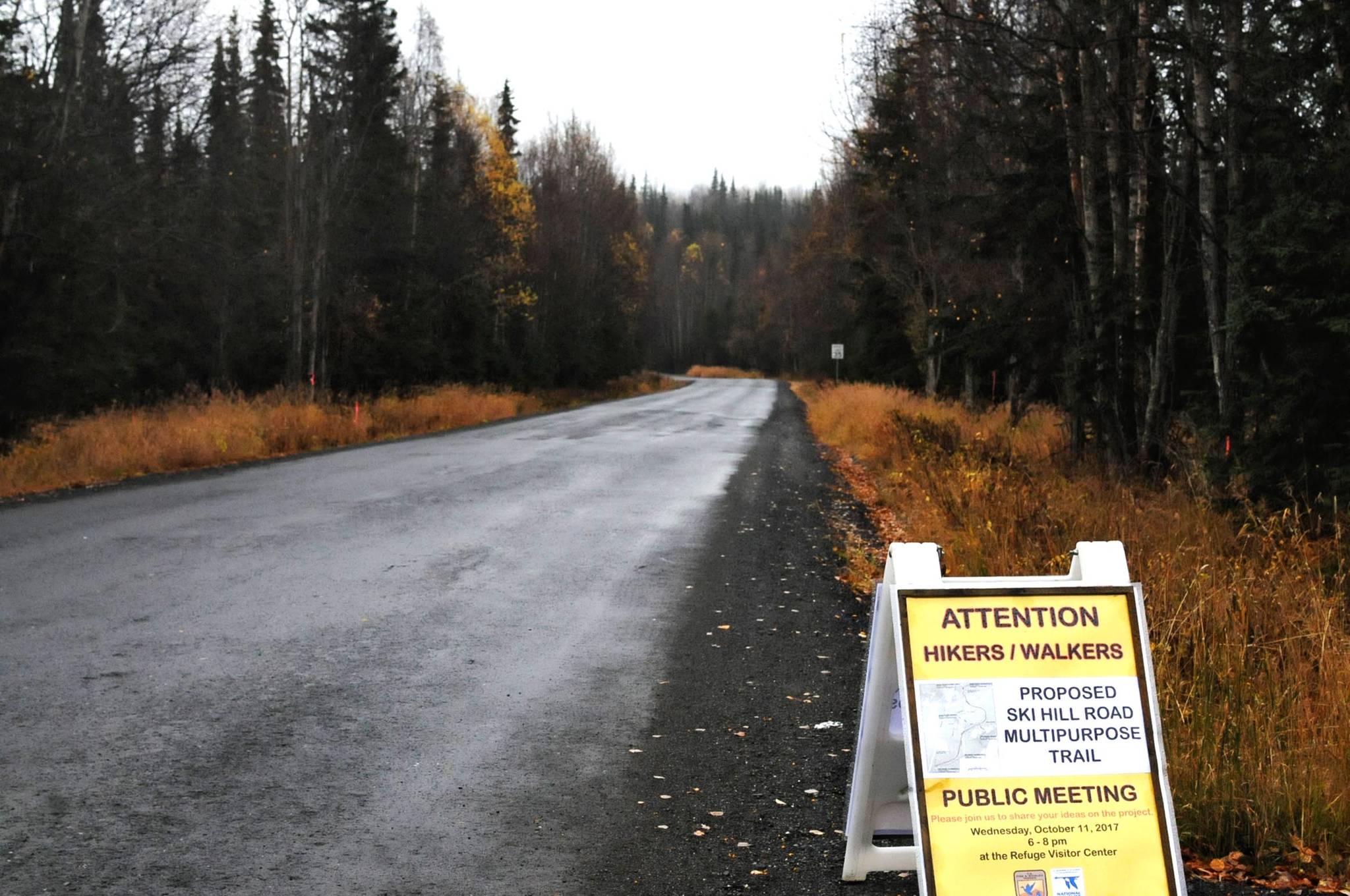 A sign advertising a public meeting about the plan for a multipurpose trail alongside Ski Hill Road stands alongside the road itself Thursday, Oct. 12, 2017 in Soldotna, Alaska. Many people choose to walk the road, which winds into the woods near the Kenai National Wildlife Refuge Visitor’s Center, for exercise, but there have been concerns in the past about conflict between cars and pedestrians on the road. The refuge and the Federal Highway Administration are in the process of planning a pedestrian pathway somewhere along the road to help divert foot traffic away from the road itself. (Photo by Elizabeth Earl/Peninsula Clarion)
