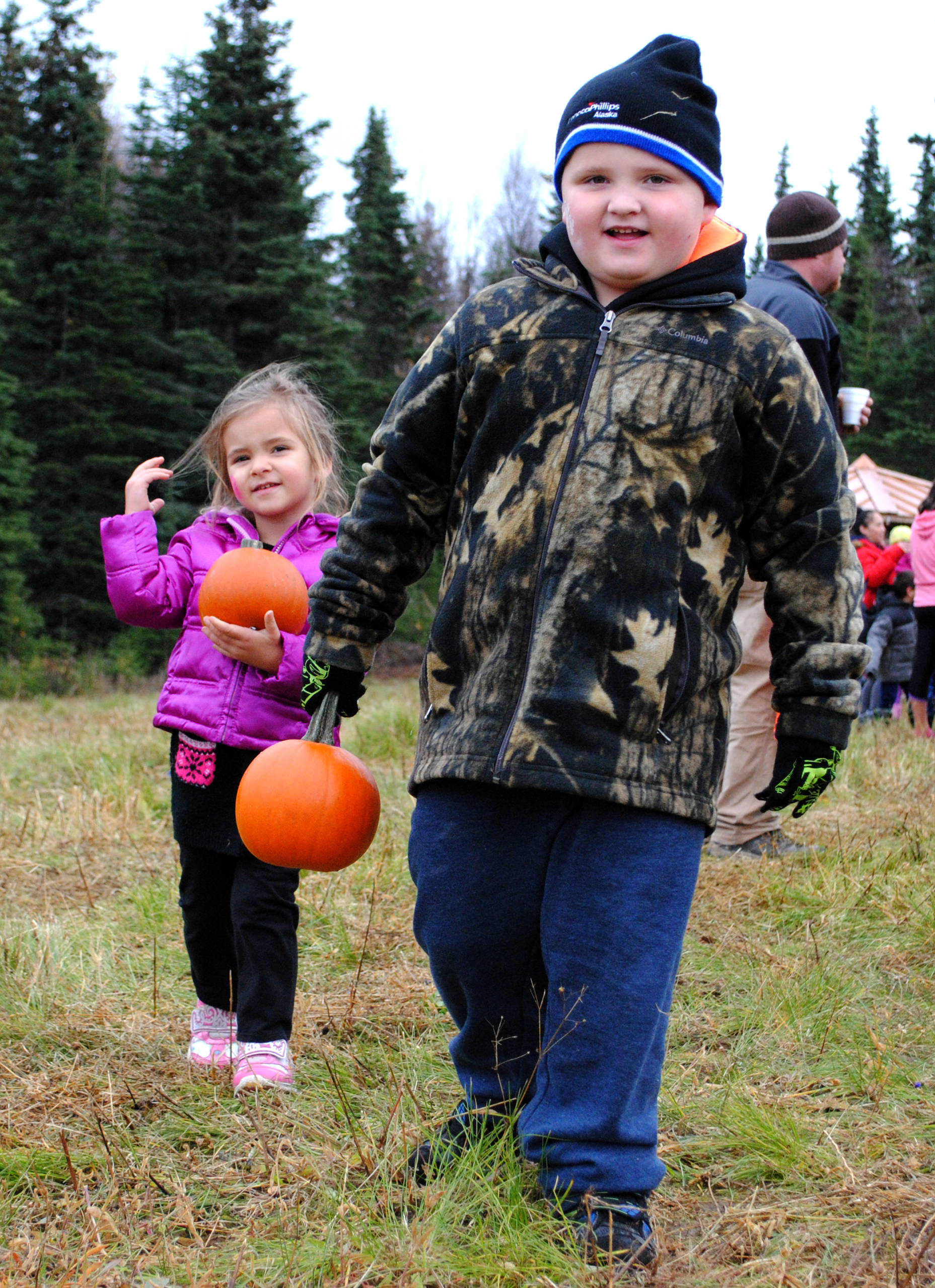 Jasper and Madison Dormady carry their pumpkins through Lawton Acres during the fall pumpkin festival in Kenai, Alaska on Oct. 14, 2017. (Photo by Kat Sorensen/Peninsula Clarion)