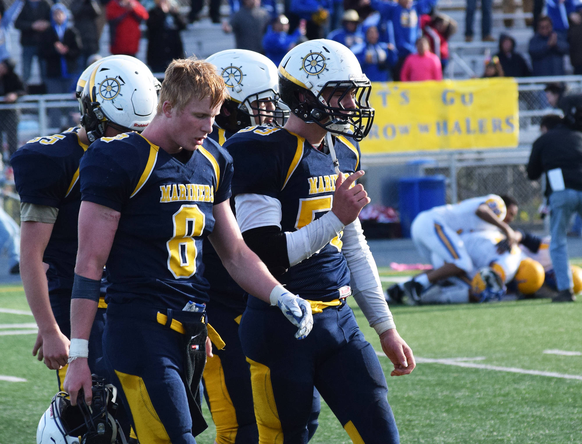 Homer senior Teddy Croft (8) walks off the field with a group of teammates Saturday while the Utqiagvik Whalers celebrate in the ASAA First National Bank Division III state championship at Machetanz Field in Palmer. (Photo by Joey Klecka/Peninsula Clarion)