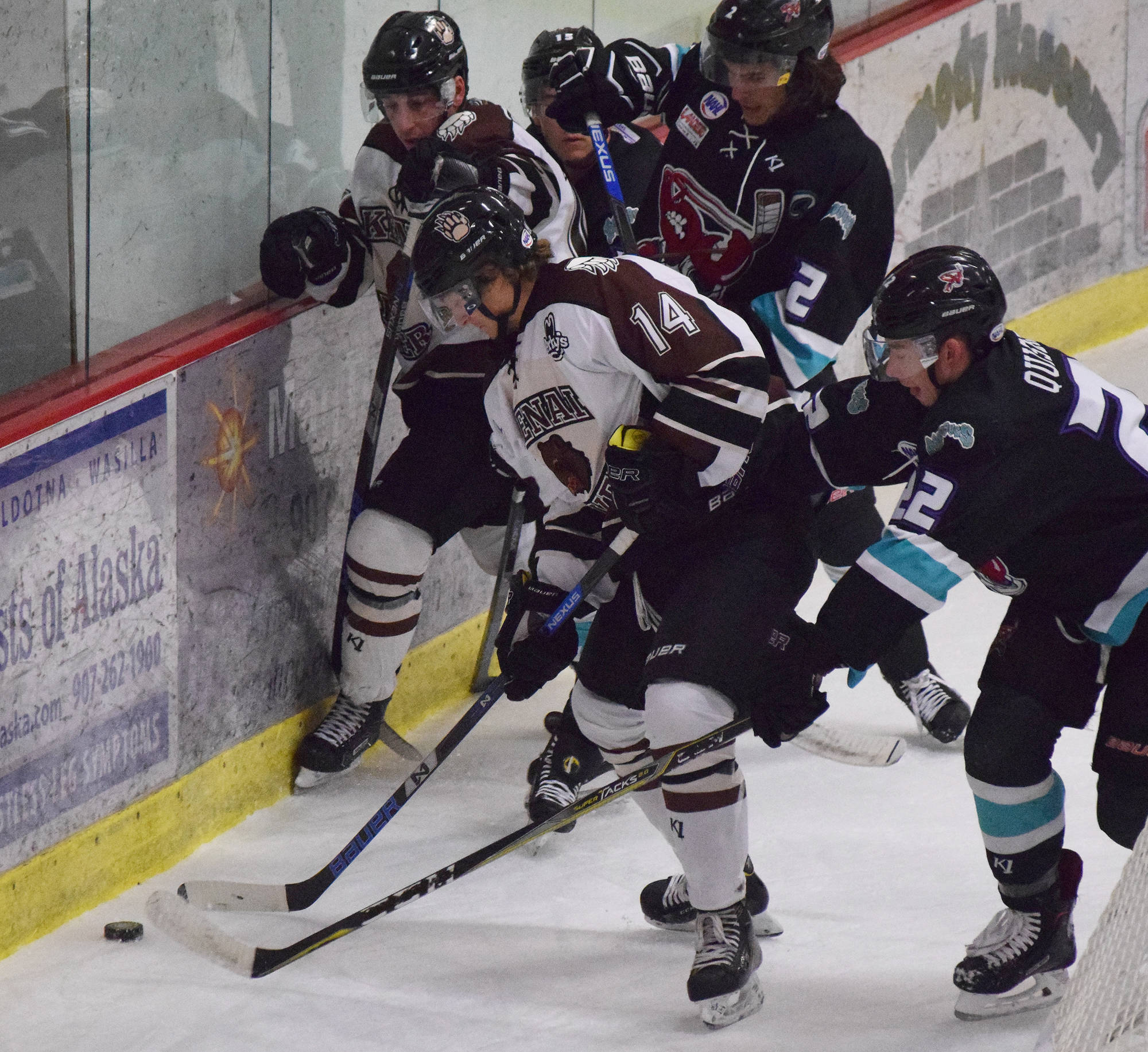 Kenai River’s Ross Hanson (14) and David Kaplan wrestle for puck control against Shreveport’s Cole Quisenberry (22) and Dominick Procopio Friday night at the Soldotna Regional Sports Complex. (Photo by Joey Klecka/Peninsula Clarion)