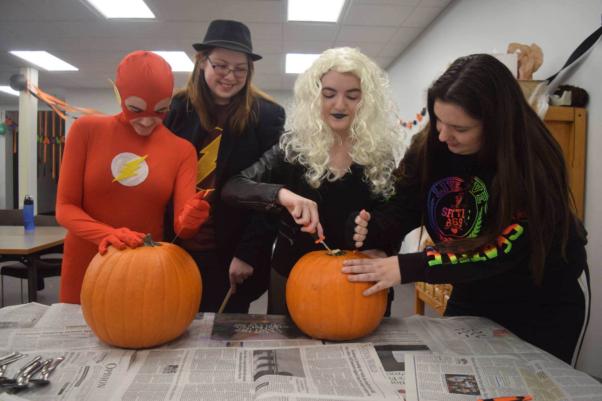 Tori Giles, left, Emilie Grimes, Torile Giles and Arin Reger carve pumkings at the Soldotna Public Library on Saturday, October 21, 2017 during the library’s teen halloween party. The group donned costumes from The Flash, including The Flash, Killer Frost and Harrison Wells. (Photo by Kat Sorensen/Peninsula Clarion)