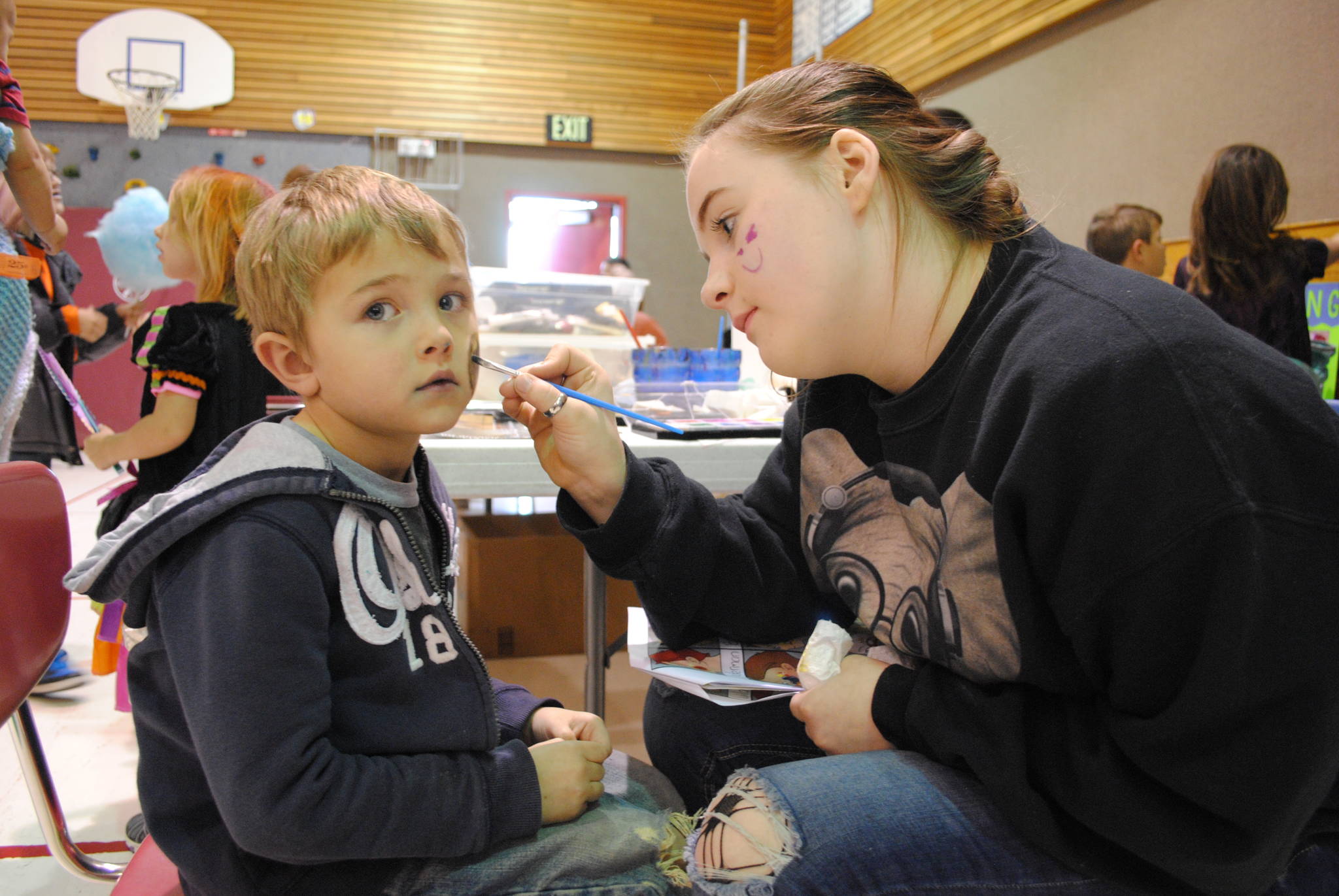 TOP: Delaney Duck, an eighth-grader at Kenai Middle School, paints Kaiden Tressler’s face during the Mountain View Elementary School’s carnival on Thursday, Oct. 19 in Kenai. All proceeds from the carnival go towards student activities, like field trips, according to Principal Karl Kircher.  RIGHT: Parker Wolverton participates in the cake walk during the Mountain View Elementary School carnival on Thursday, Oct. 19 in Kenai. (Photo by Kat Sorensen/Peninsula Clarion)