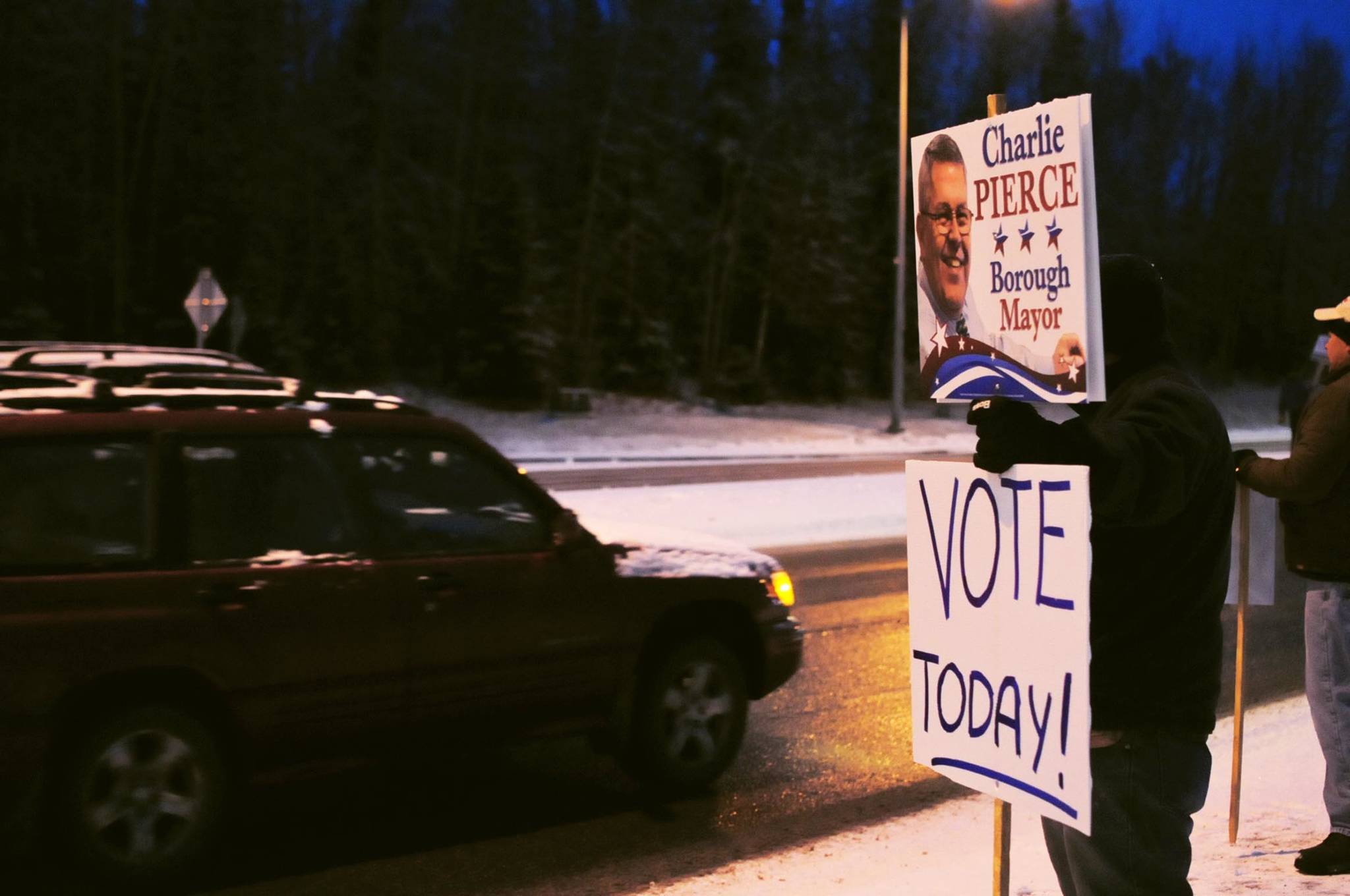 A car passes supporters waving signs for borough mayoral candidate Charlie Pierce at the intersection of the Sterling Highway and the Kenai Spur Highway on Tuesday, Oct. 24, 2017 in Soldotna, Alaska. Kenai Peninsula voters chose between Pierce and candidate Linda Hutchings for the office of borough mayor on Tuesday. (Photo by Elizabeth Earl/Peninsula Clarion)