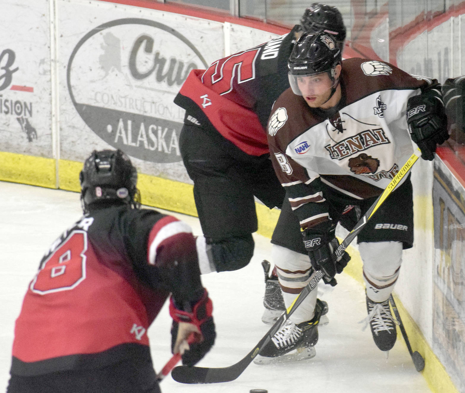 Kenai River Brown Bears forward Gil Garcia works out of the corner against Minnesota Magicians defensemen Caydon Meyer (8) and Charlie Weiand (55) on Thursday, Oct. 26, 2017, at the Soldotna Regional Sports Complex. (Photo by Jeff Helminiak/Peninsula Clarion)