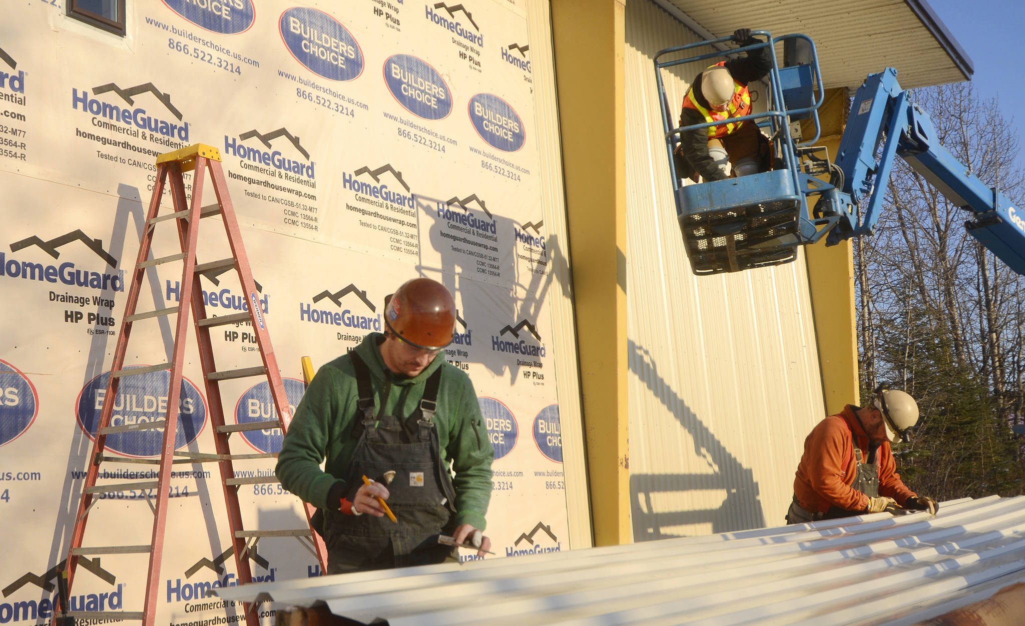 A crew from Gebhardt Construction puts metal siding on a Kenai building — erected as office space in 1968 but vacant since the mid-1980s, and now set to open in early 2018 as an Extreme Fun Center amusement hall and arcade — on Wednesday, Nov. 8, 2017 in Kenai, Alaska. John Schweiger, whose company Coming Attractions Theatres has owned the building and the adjacent Kenai Cinema since May, said crews are finishing the exterior before colder weather sets in, and will spend the winter refurbishing the inside, so the center “will hopefully be open for spring break.” Coming Attractions is “about 80 to 90 percent” through the process of deciding what attractions the center will feature, Schweiger said. (Ben Boettger/Peninsula Clarion)