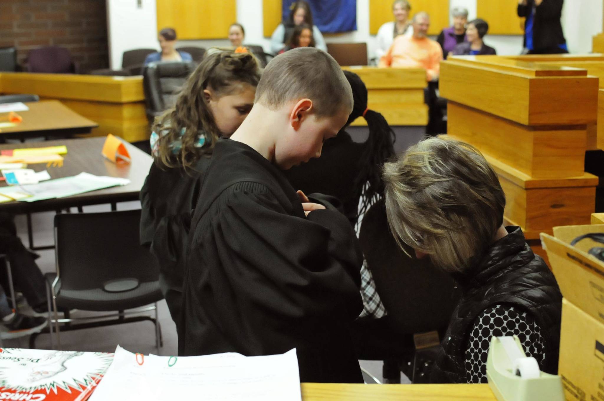 Kalifornsky Beach Elementary School 2nd grade teacher Kelly Brewer helps student Levi Kirby into his judge’s robes before the class begins its mock trial of “Arthur T. Grinch” based on the Dr. Seuss classic “How the Grinch Stole Christmas” on Thursday, Nov. 9, 2017 in Kenai, Alaska. The class has been studying civics and learning about the court process and put on a mock sentencing hearing, complete with witnesses and a jury composed of students’ parents and K-Beach Elementary Principal Nate Crabtree. (Photo by Elizabeth Earl/Peninsula Clarion)