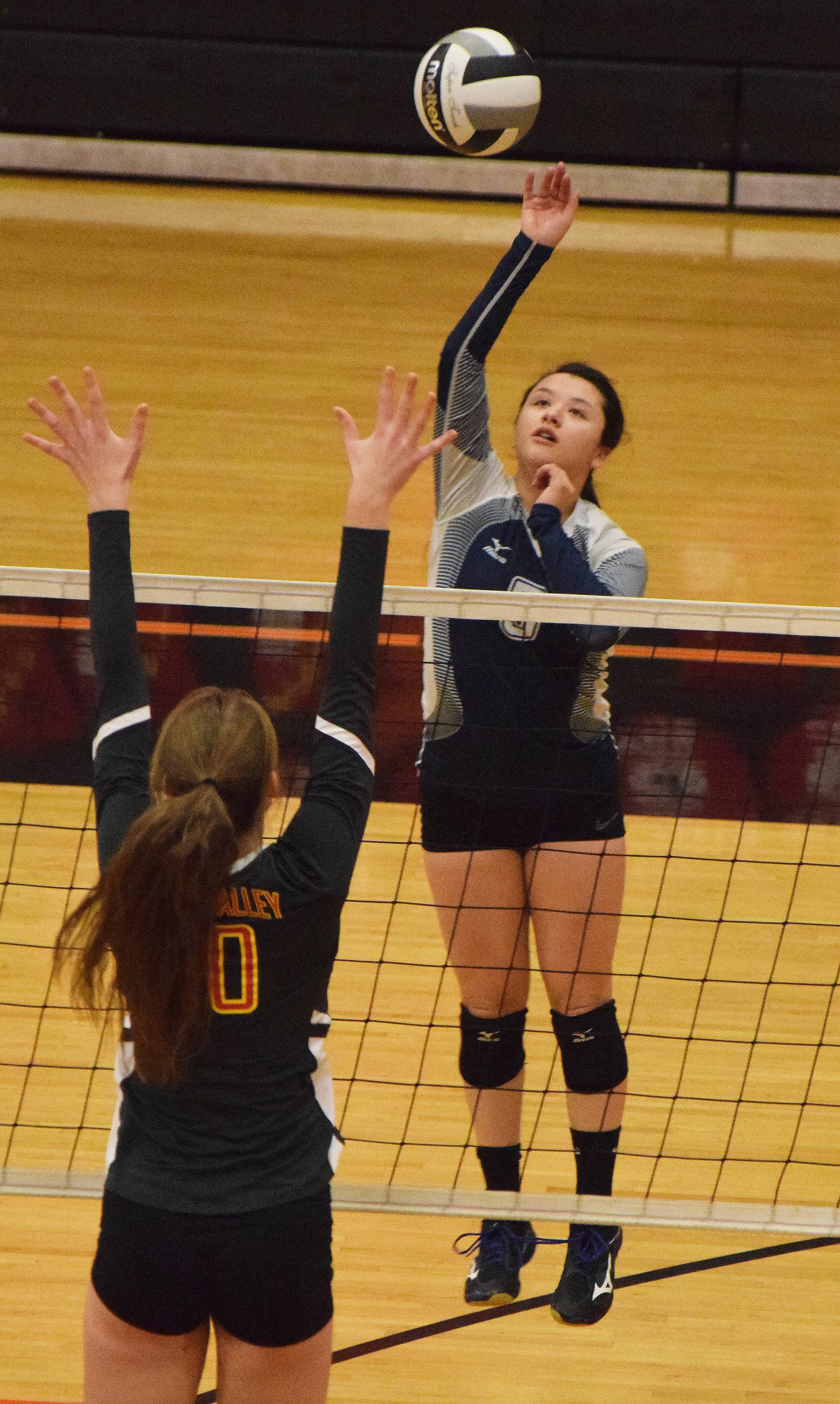 Soldotna senior Shay Zener lifts a ball over West Valley blocker Sonia McGaffigan Friday at the Class 4A state volleyball tournament at West High School. (Photo by Joey Klecka/Peninsula Clarion)