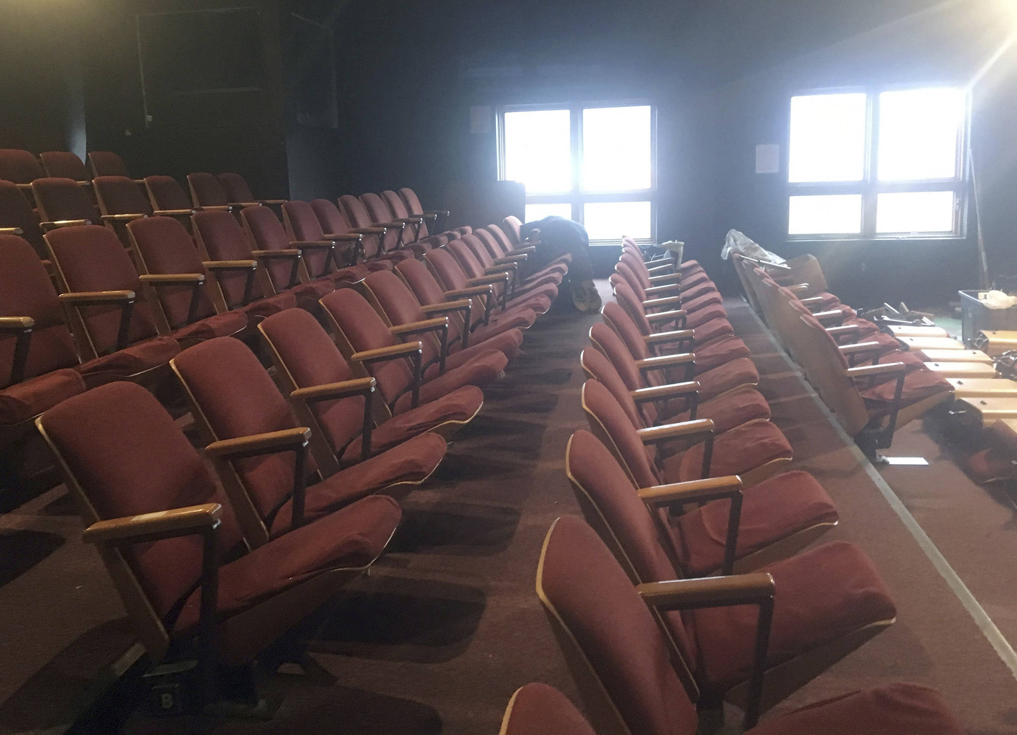 In this Monday, Oct. 30, 2017 photo, Martin Buser unfastens theater seats in the theater at the Alaska Fine Arts Academy in Eagle River, Alaska. The seats were being removed as the theater vacated the space, which had been its home for 11 years. A board member said the arts academy is in the process of looking for a new permanent home. (Matt Tunseth/Chugiak-Eagle River Star via AP)