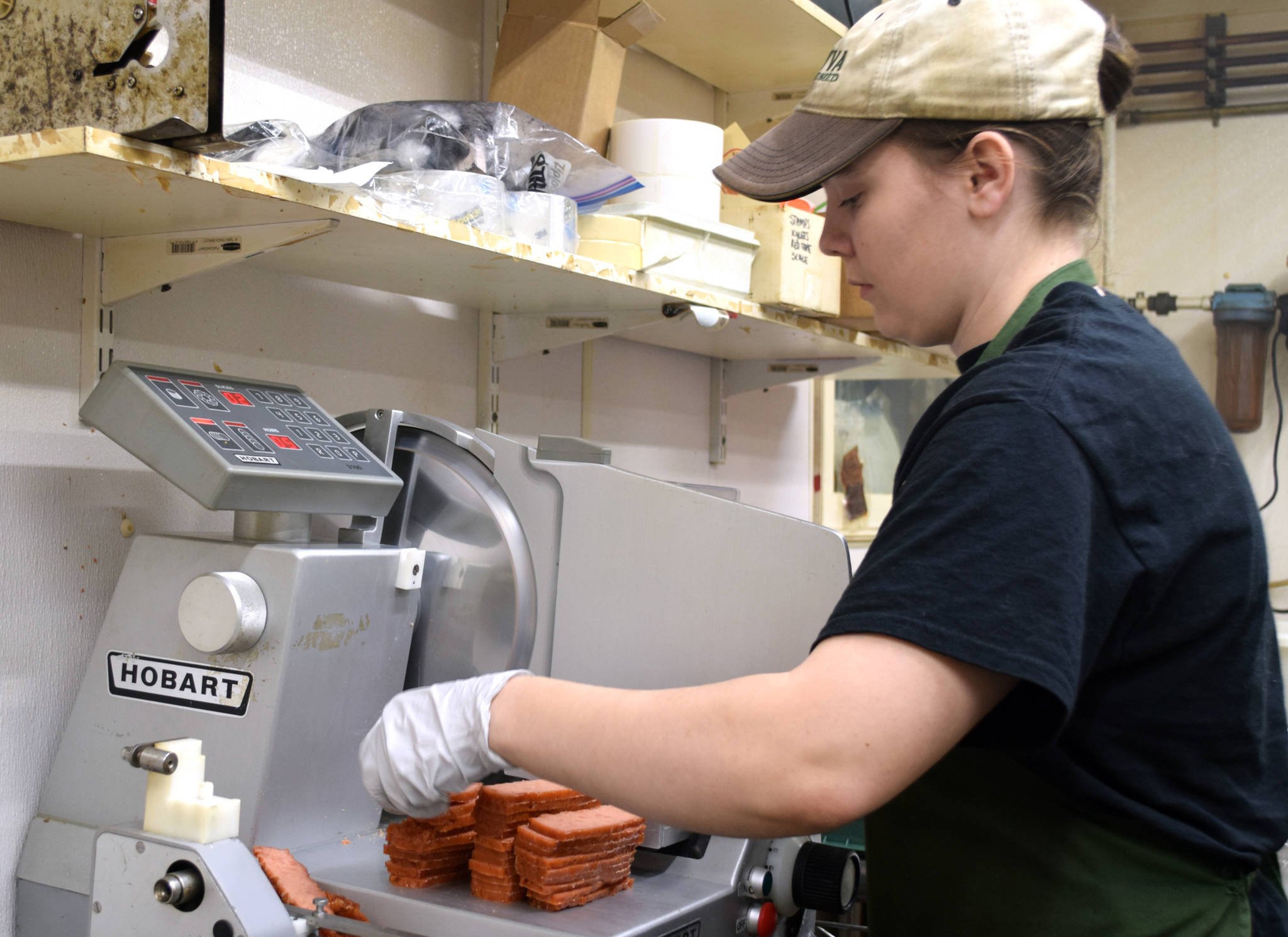Middle: Hannah, an employee of Tustumena Smokehouse in Tustumena, slices a batch of Kylee’s Alaska Salmon Bacon after it’s been processed through the smoker.