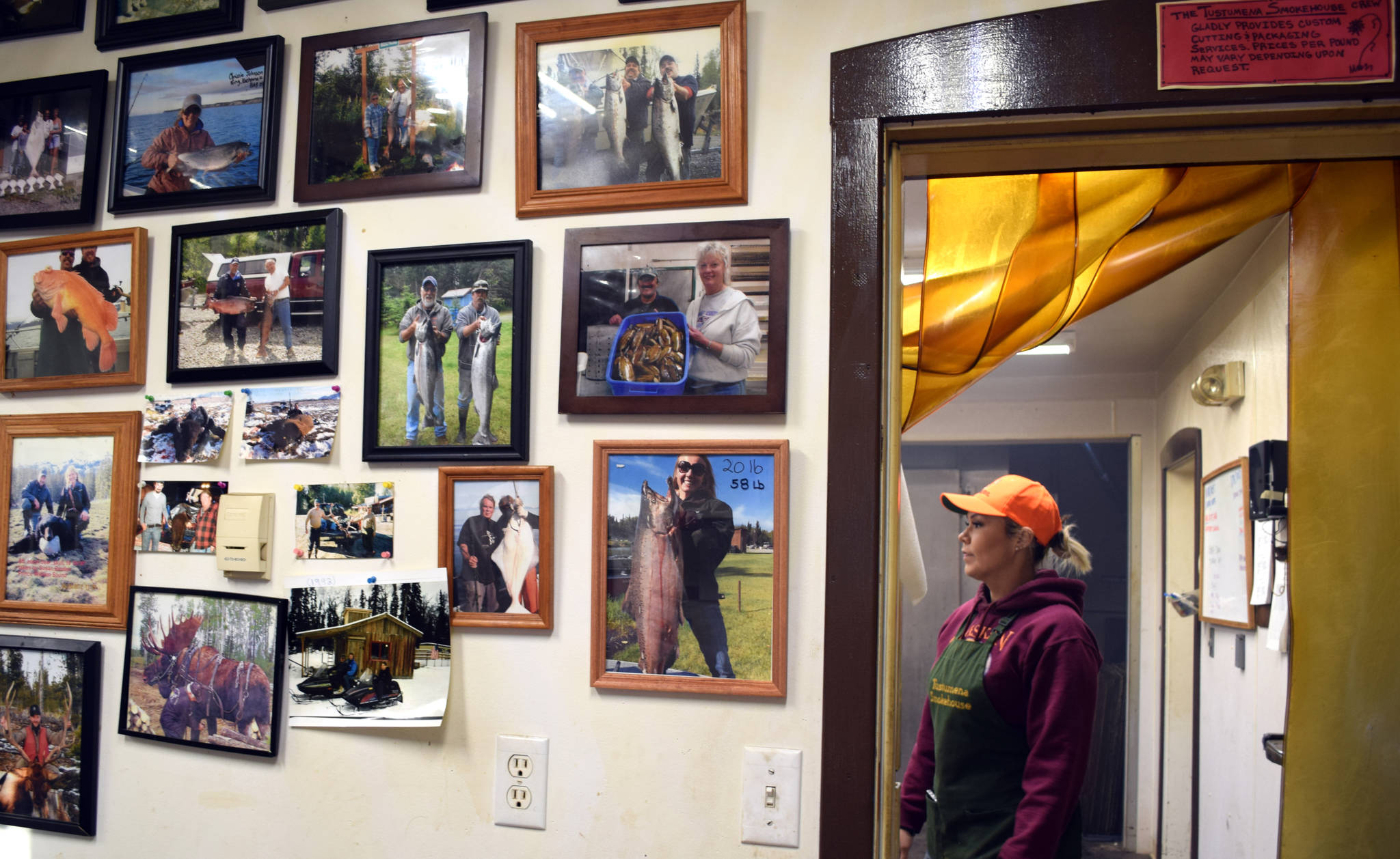 Top: Trisha Whitney, an employee of Tustumena Smokehouse, stands just past the doorway between the smokehouse and the office, which features a wall lined with trophies of summer’s past.