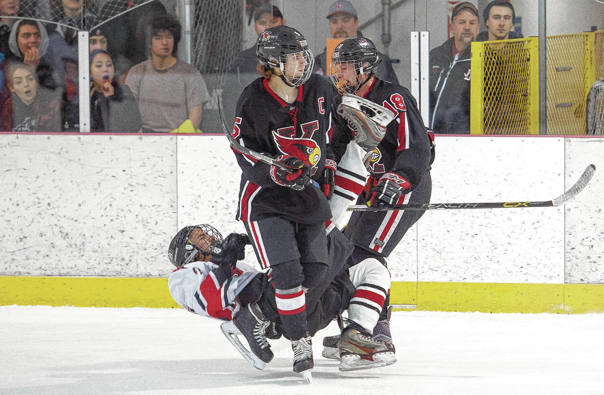 Juneau-Douglas’s Blake Bixby is knocked down by Kenai’s Jakeb O’Brien, right, in front of Kenai’s Levi Mese at Treadwell Arena on Friday, Nov. 17, 2017. O’Brien was called for roughing on the play. (Photo by Michael Penn/Juneau Empire)